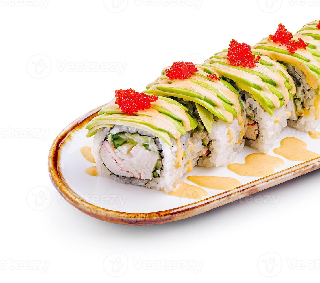 Delicious sushi roll topped with avocado and fish roe served on a decorative plate photo