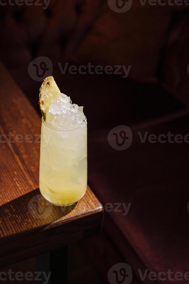 Refreshing cocktail served in a glass with crushed ice and a pineapple garnish on a wooden table photo