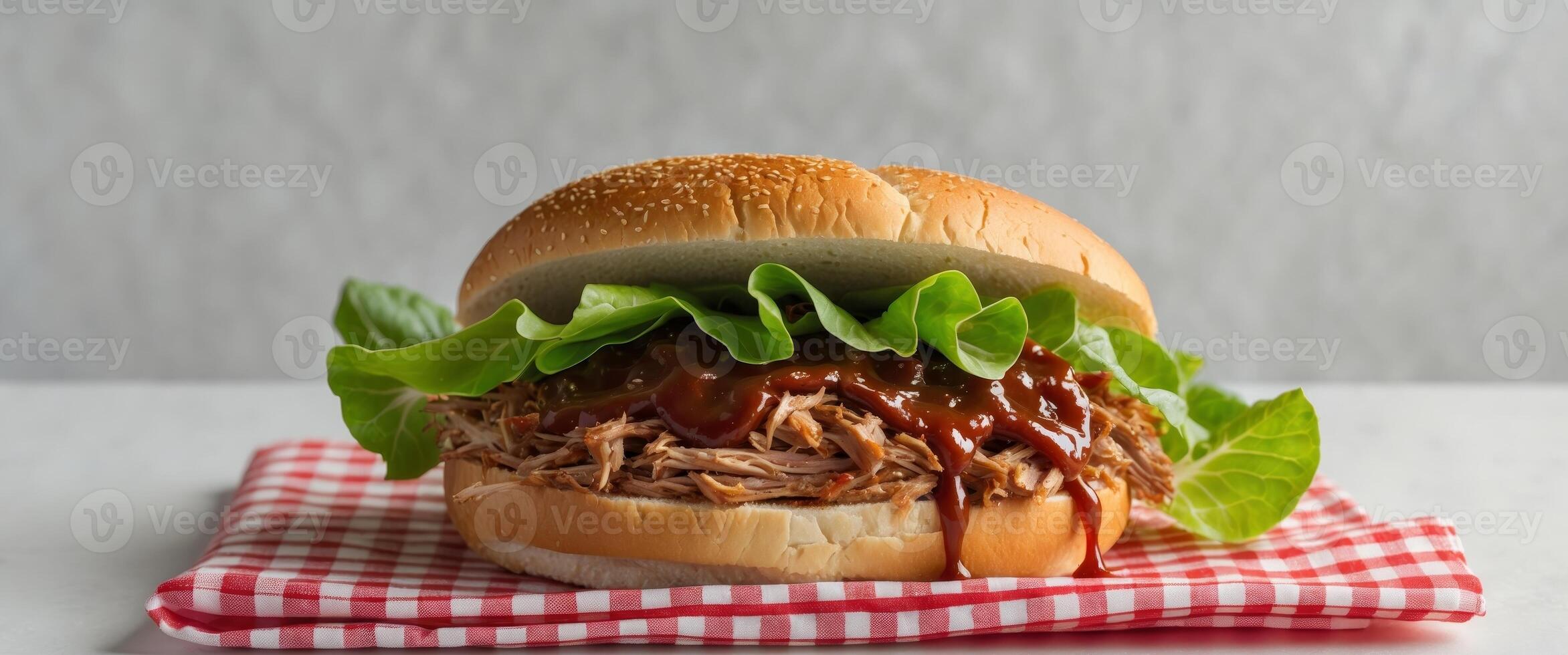 Savory Pulled Pork Sandwich with Tangy Barbecue Sauce and Crisp Lettuce on a Checkered Napkin photo