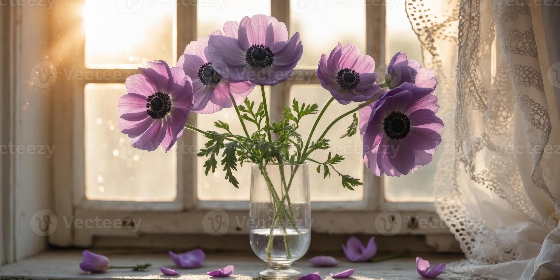 Purple anemone flowers in a glass vase on a windowsill with sunlight streaming in during daytime photo