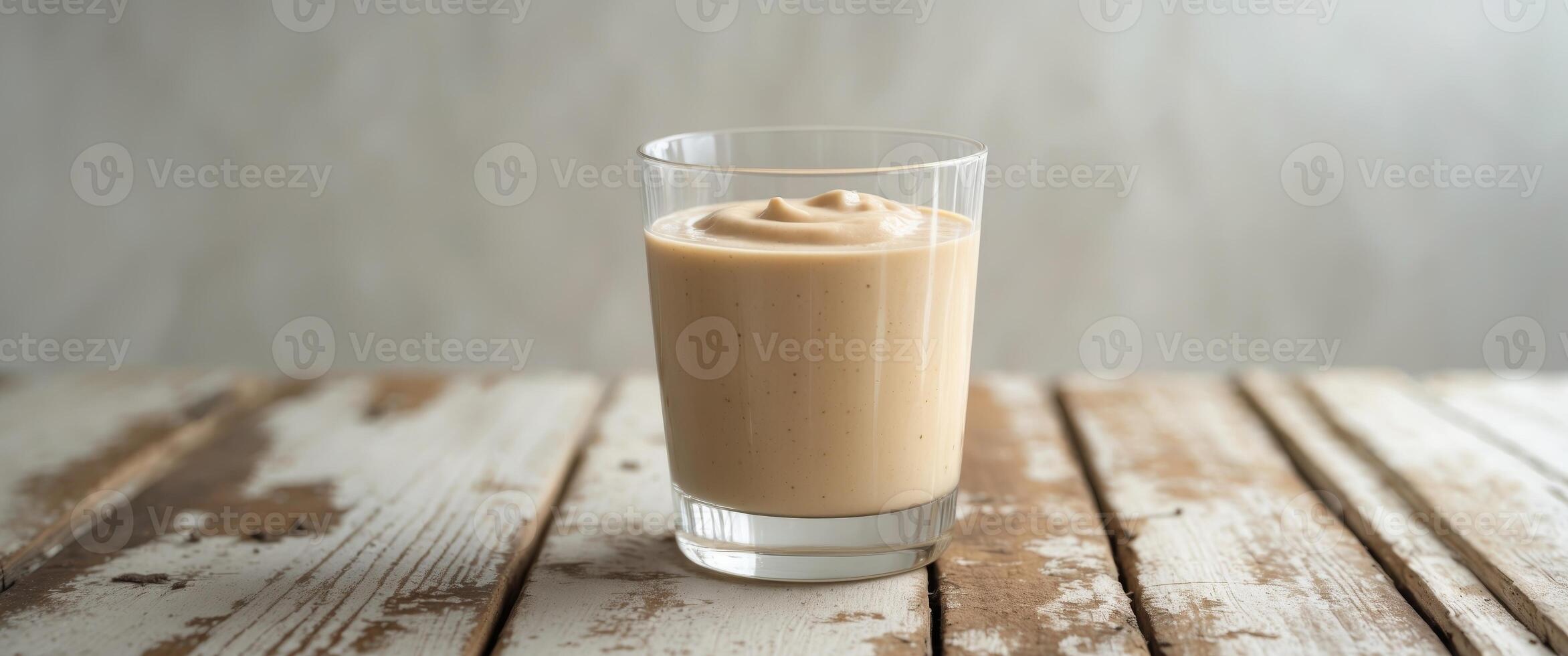 Creamy Beige Smoothie in Glass on Wooden Table photo