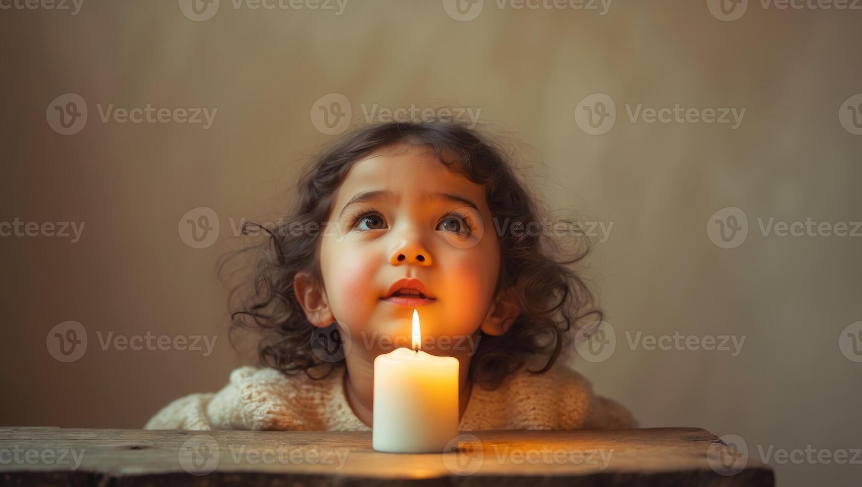 A little girl looking up at a lit candle photo