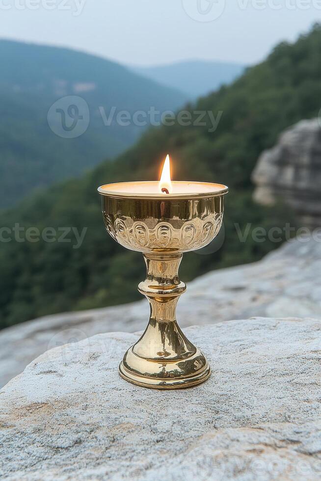 A lit offering candle sits on a rock with a mountain background photo