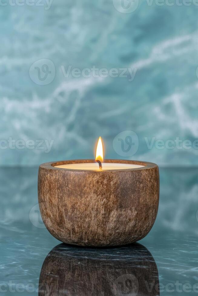 A lit candle in a wooden bowl on a reflective surface photo