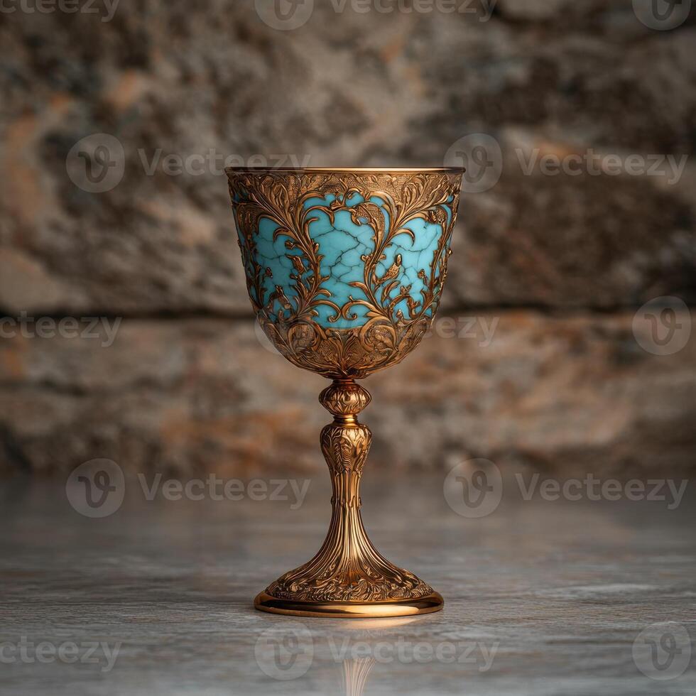 Ornate golden goblet with turquoise inlay against a stone background photo