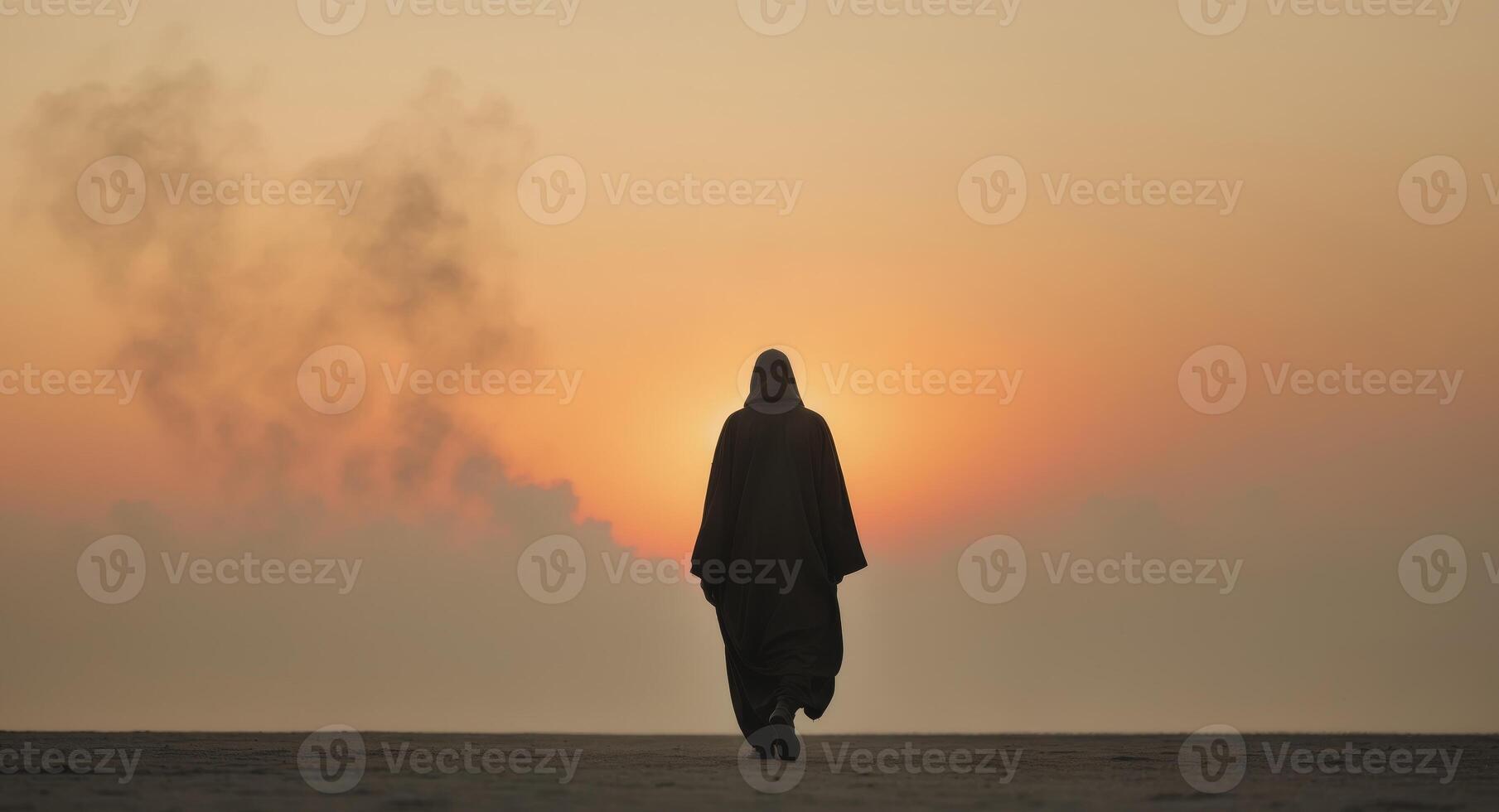 A person in a hooded robe walking across the sand photo