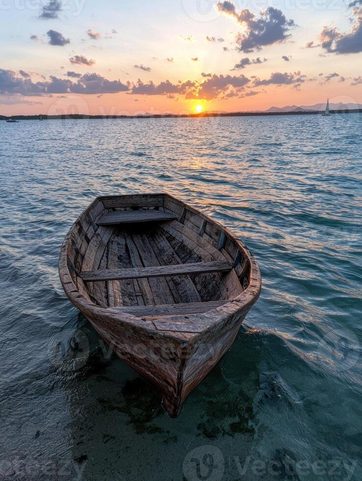 A rustic wooden rowboat rests in calm waters at sunset photo