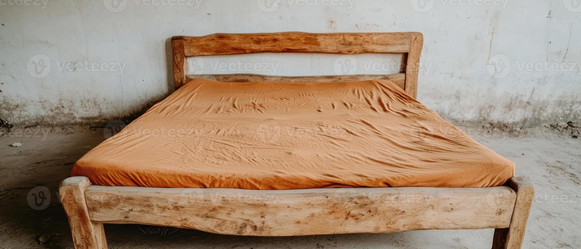 Rustic wooden bed with orange sheet in a simple room photo