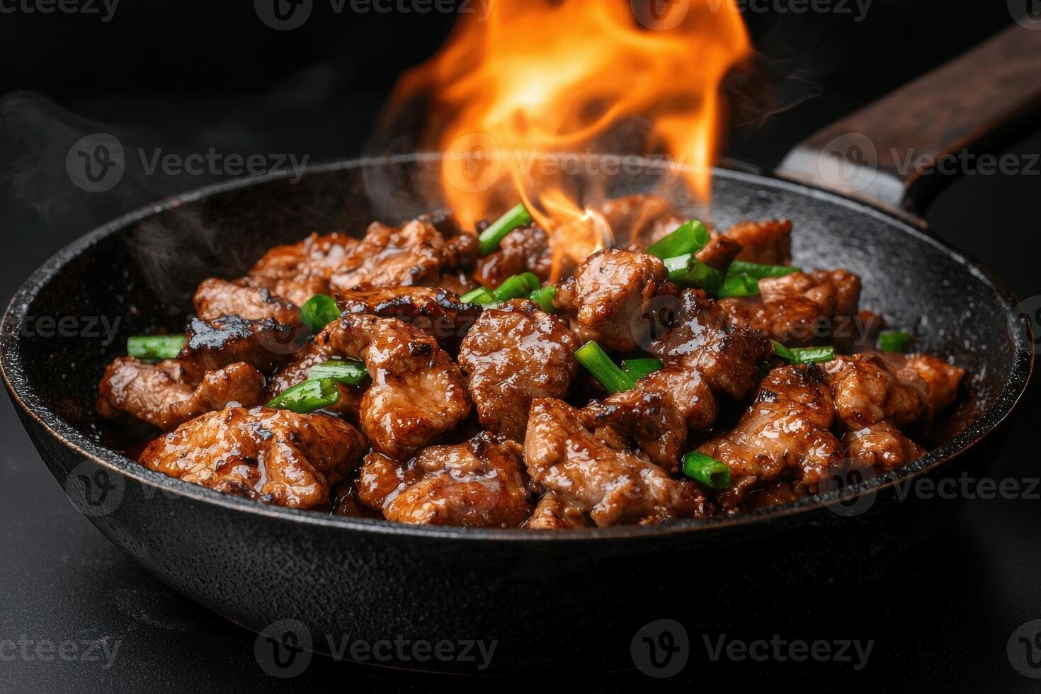 Delicious stir fried meat with green onions on a skillet with flames photo
