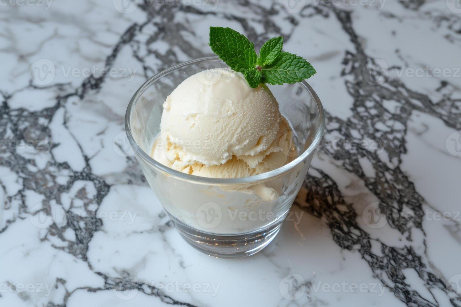 A scoop of vanilla ice cream in a glass with a mint garnish photo