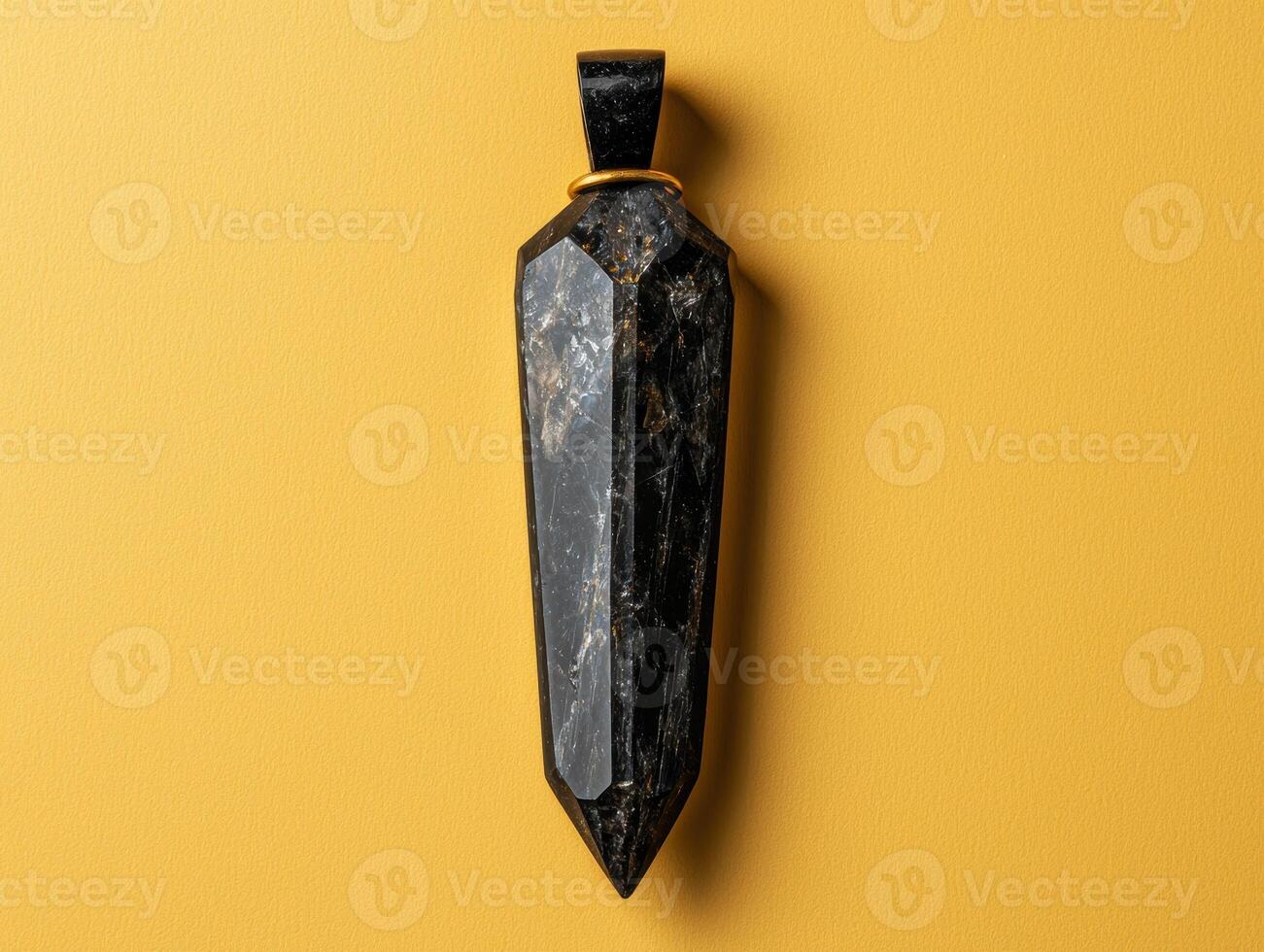 Black tourmaline crystal pendant on yellow background photo