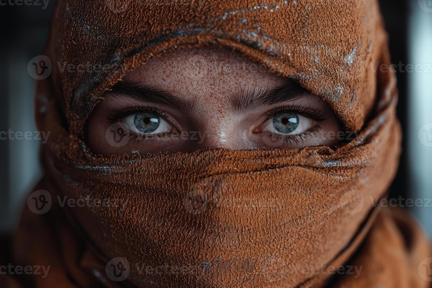 Close up of a womans face covered with a brown scarf, focusing on her eyes photo