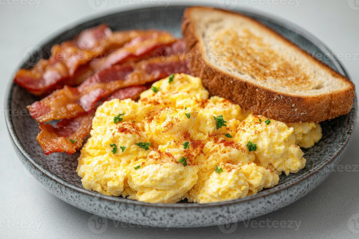 A plate of scrambled eggs, bacon, and toast photo