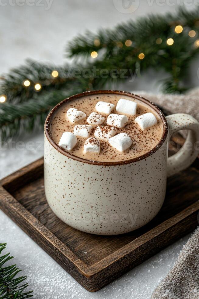 A mug of hot chocolate with marshmallows and a Christmas tree branch in the background photo