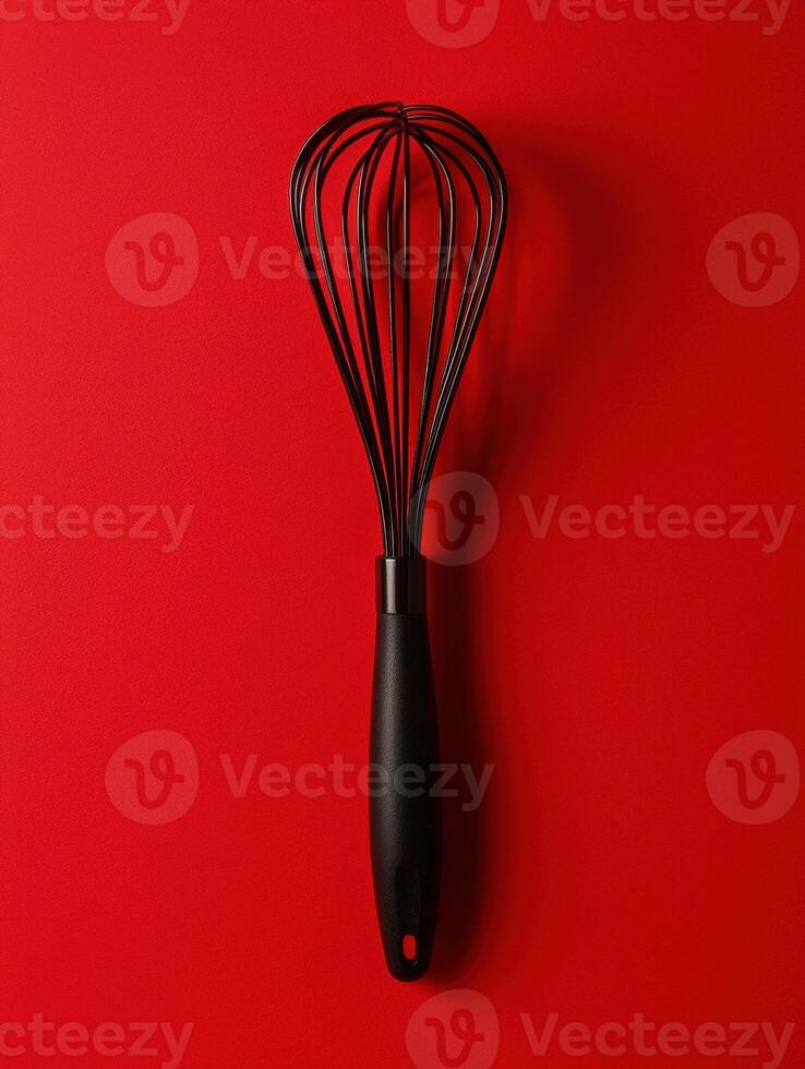A black whisk on a red background photo