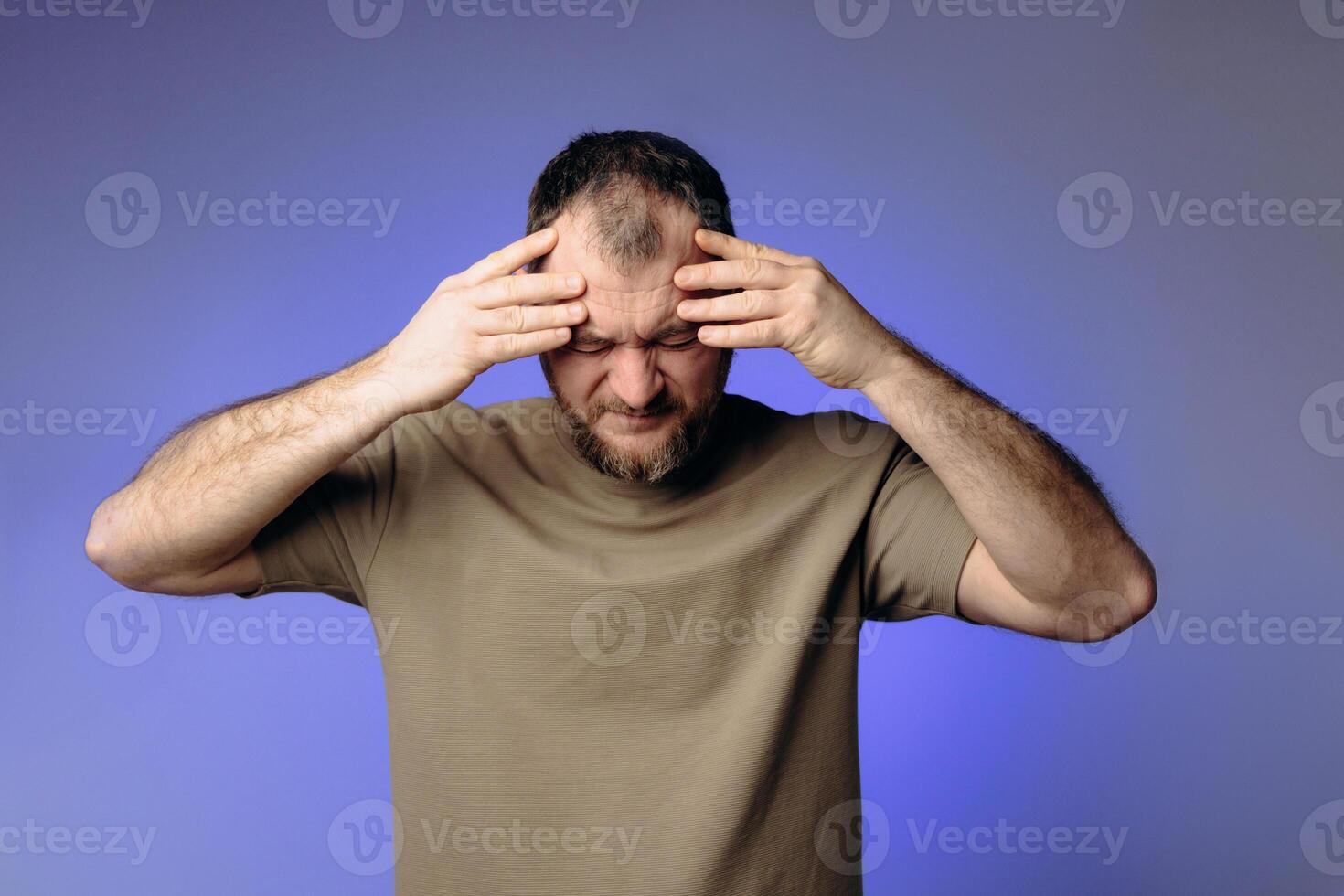 A man has a severe headache. He holds his head in his hands and massages his temples to relieve the pain in his head. Changes in atmospheric pressure affect physical condition and headaches. photo