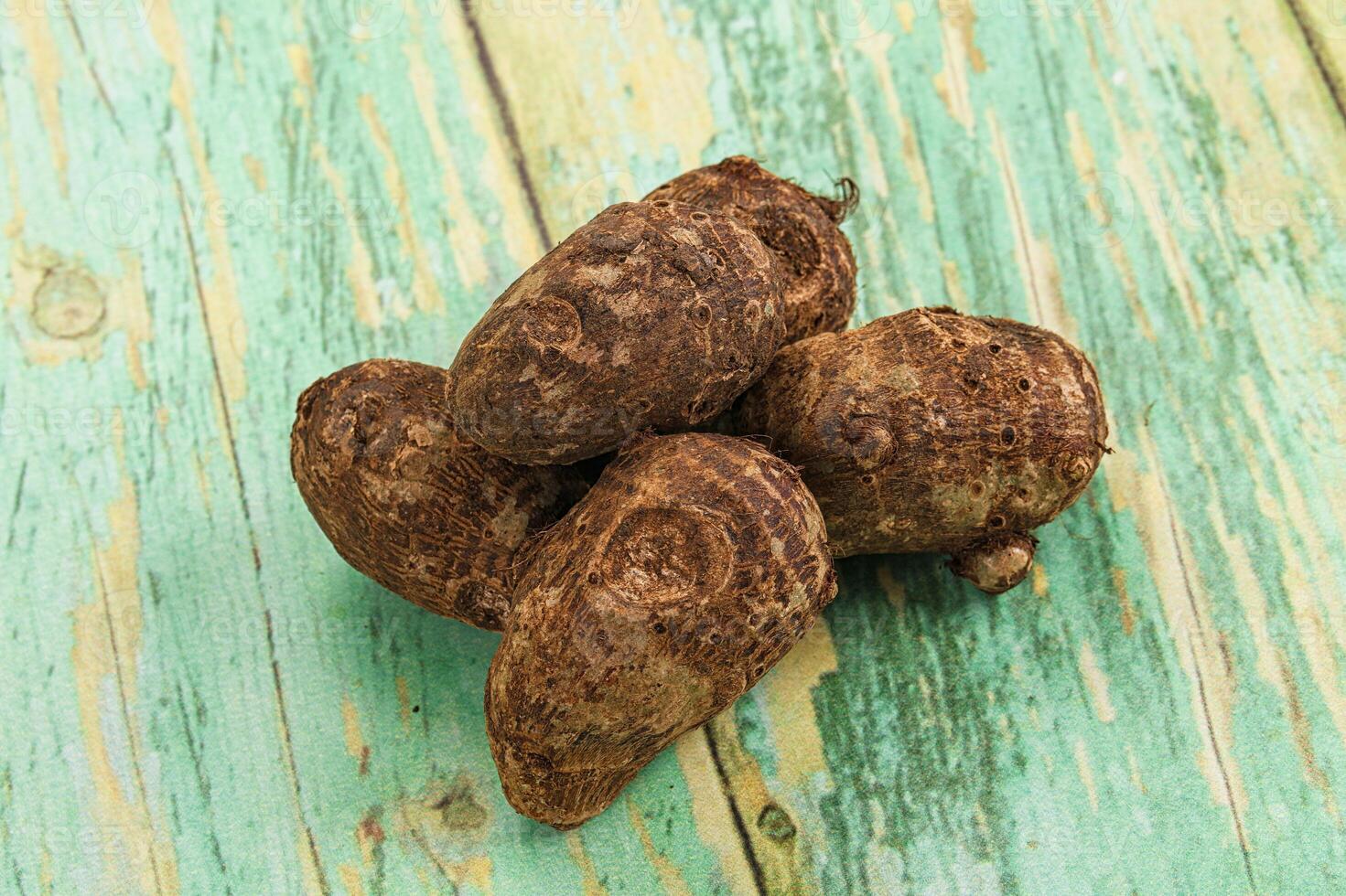 A pile of brown and green coconuts on a wooden table photo