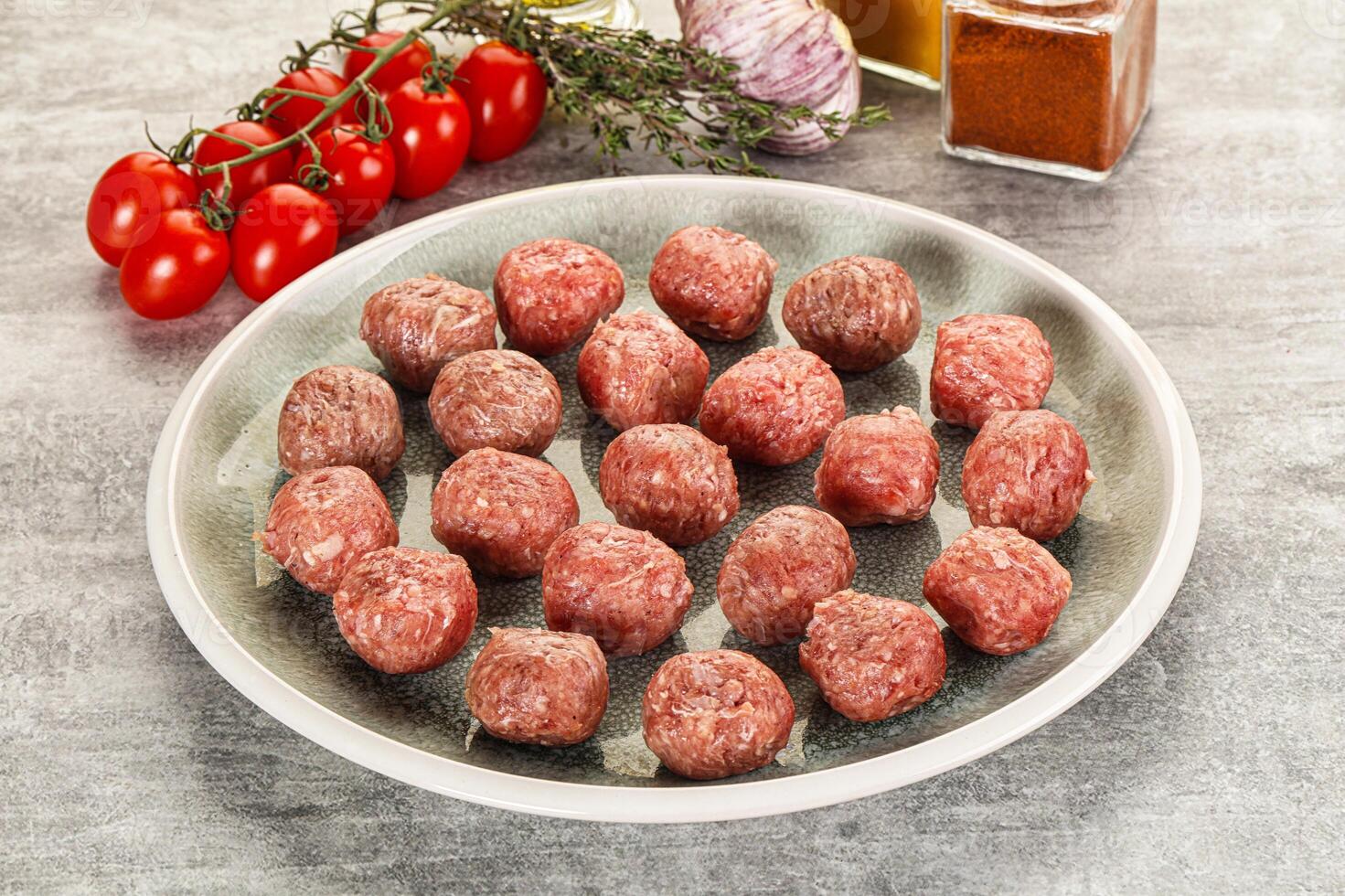 A plate of meatballs on a table next to a bowl of tomatoes photo