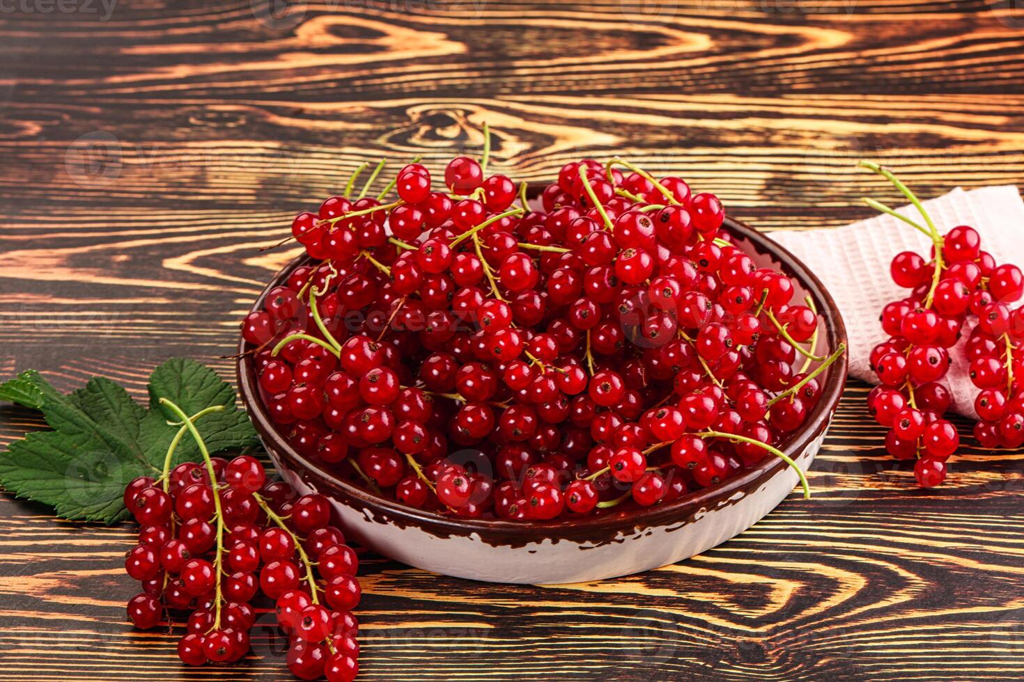 A bowl of red currants on a wooden table photo
