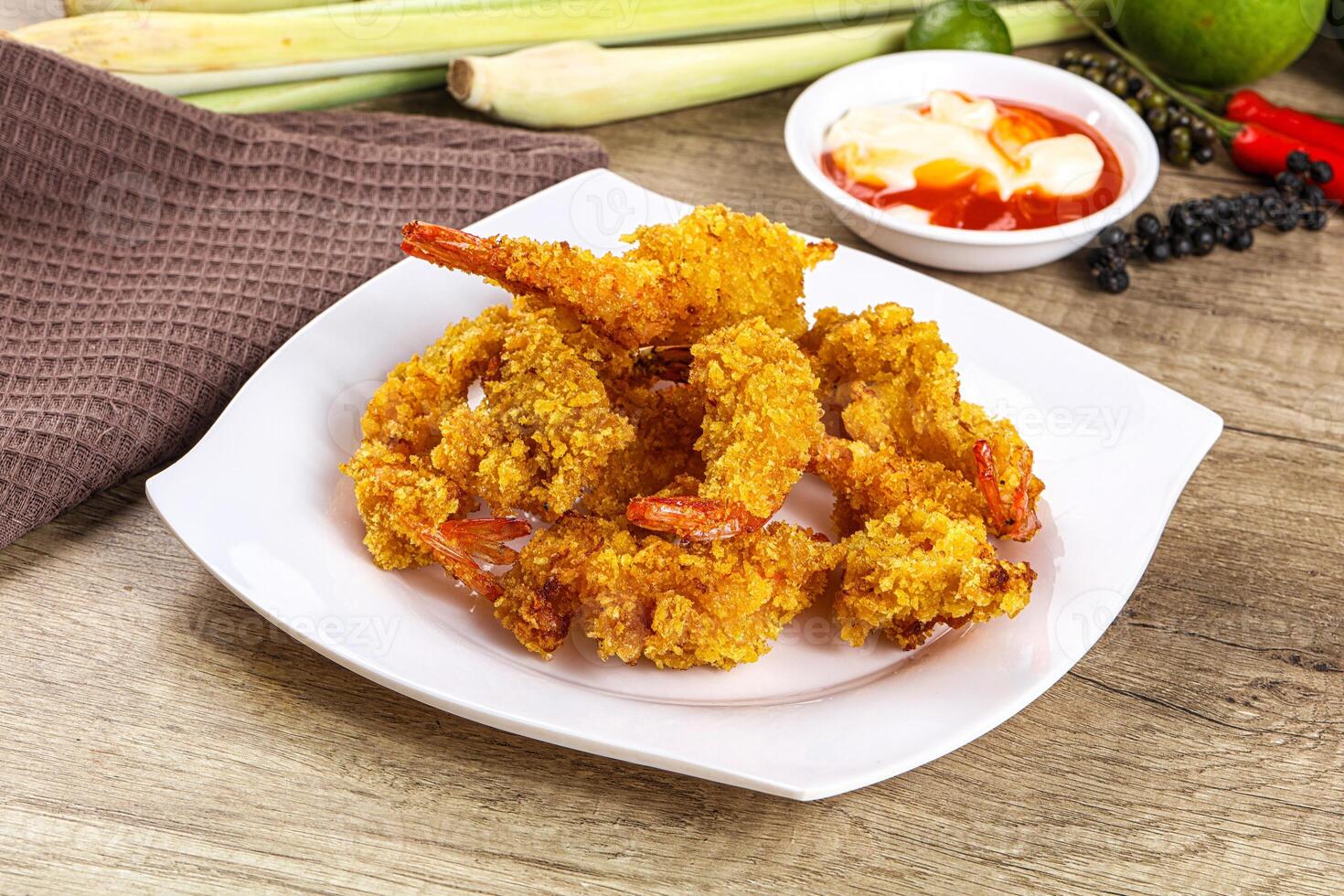 A plate of fried shrimp on a table with a bowl of sauce photo