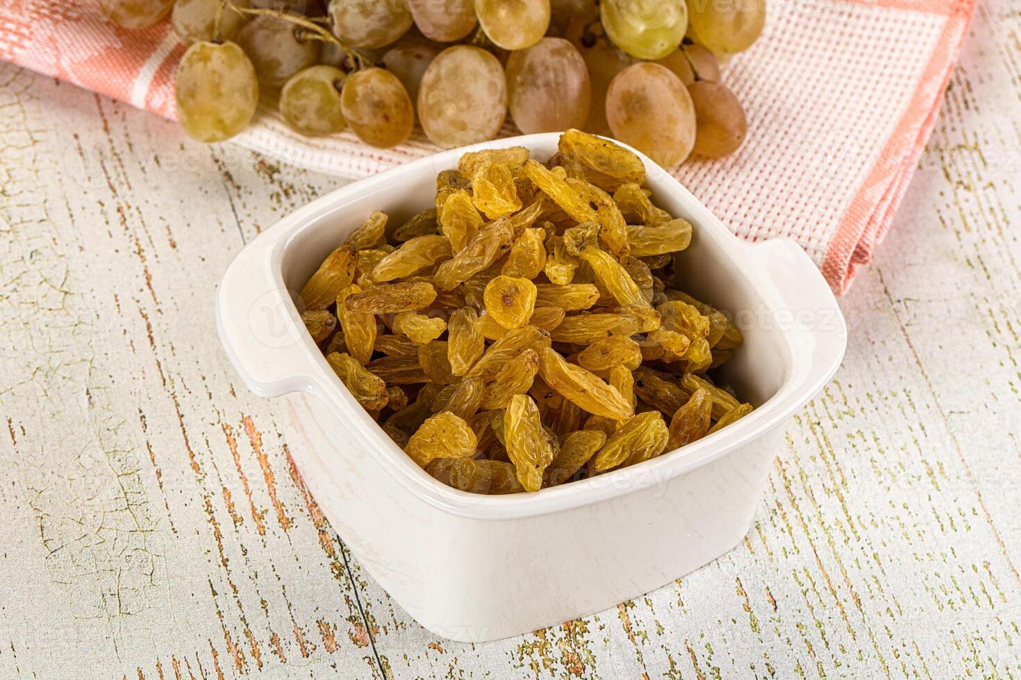 A bowl of raisins and a bunch of grapes photo
