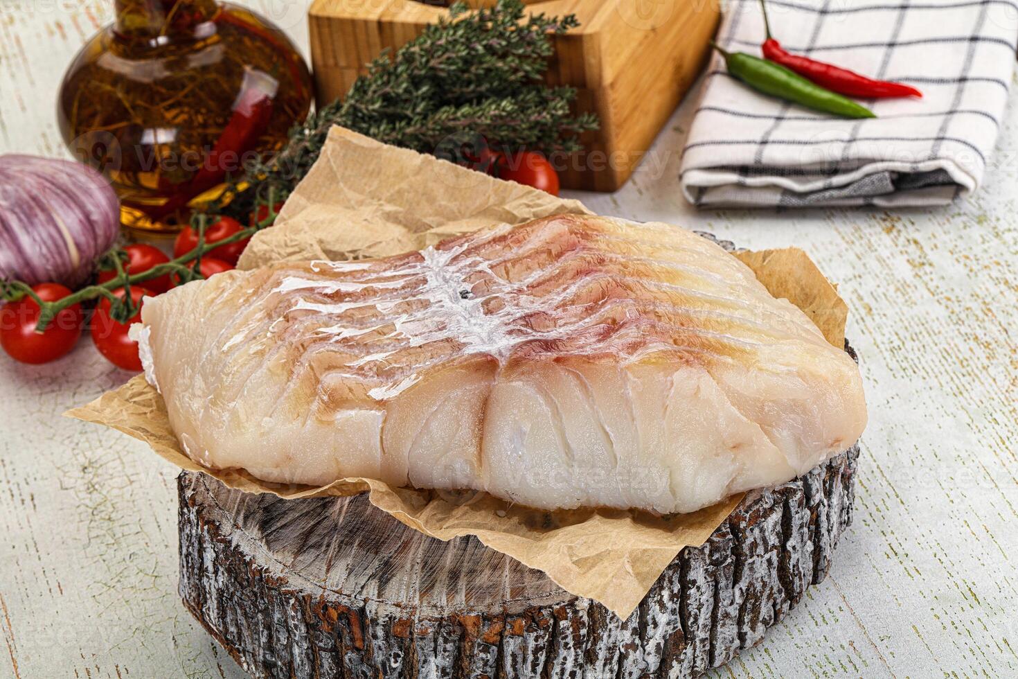 A piece of fish on a wooden table with other ingredients photo