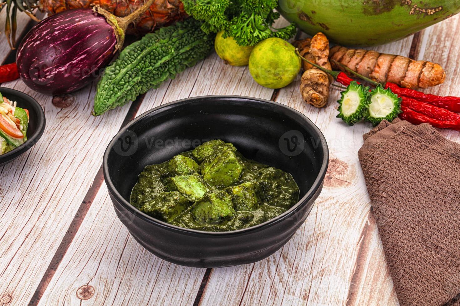 A bowl of green food on a table next to other food photo