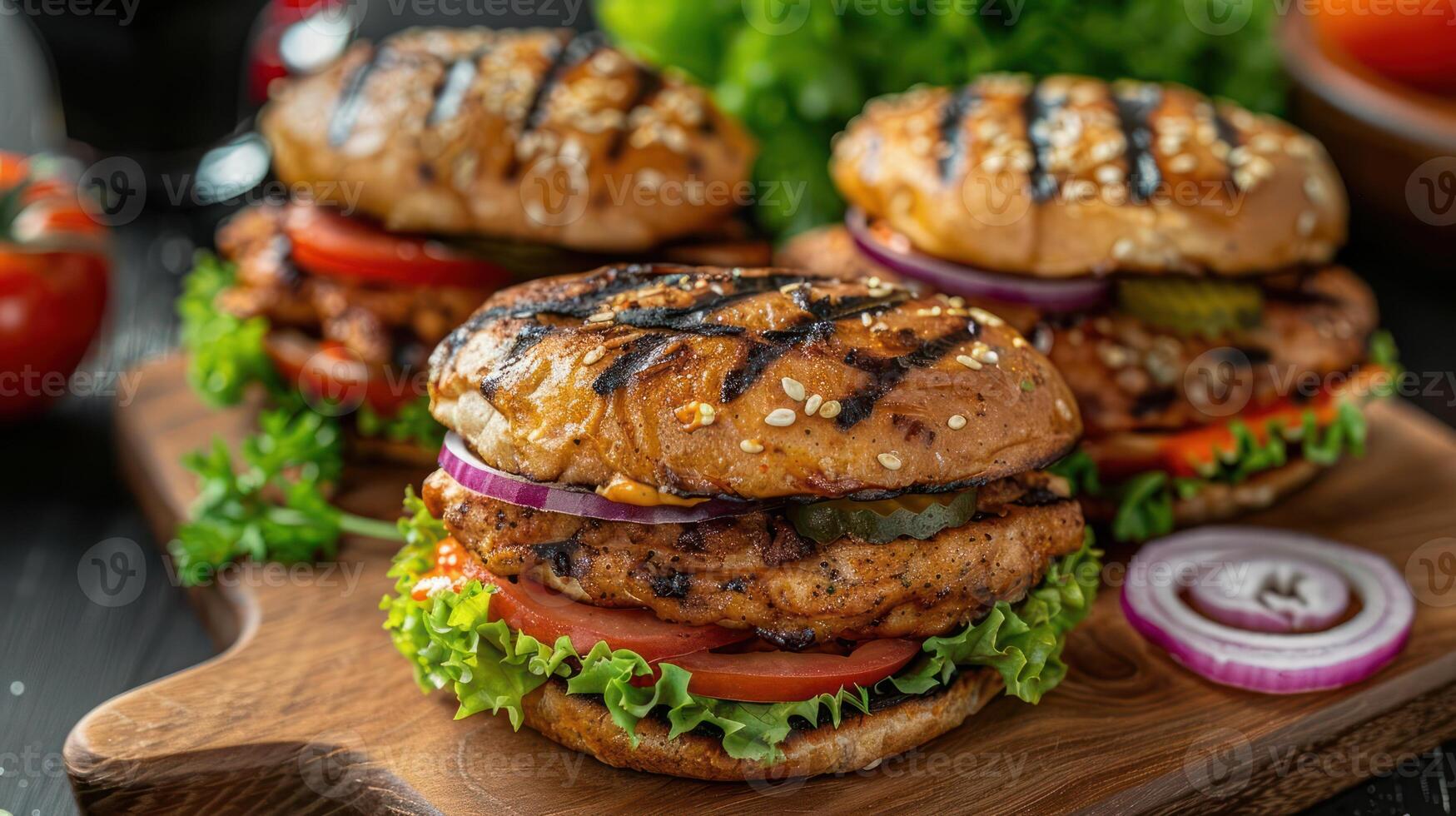 Three grilled chicken sandwiches with fresh vegetables on a wooden board. photo