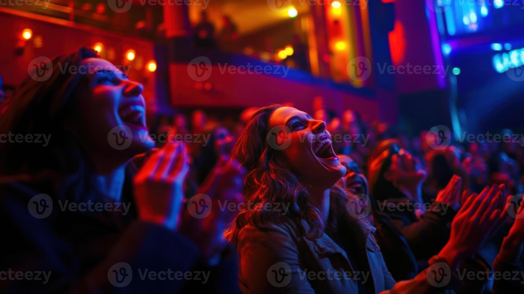 A wide shot of the studio audience reacting with laughter and applause their faces a blur of excitement under the colorful ambient lighting that cascades across the stage enhancin photo