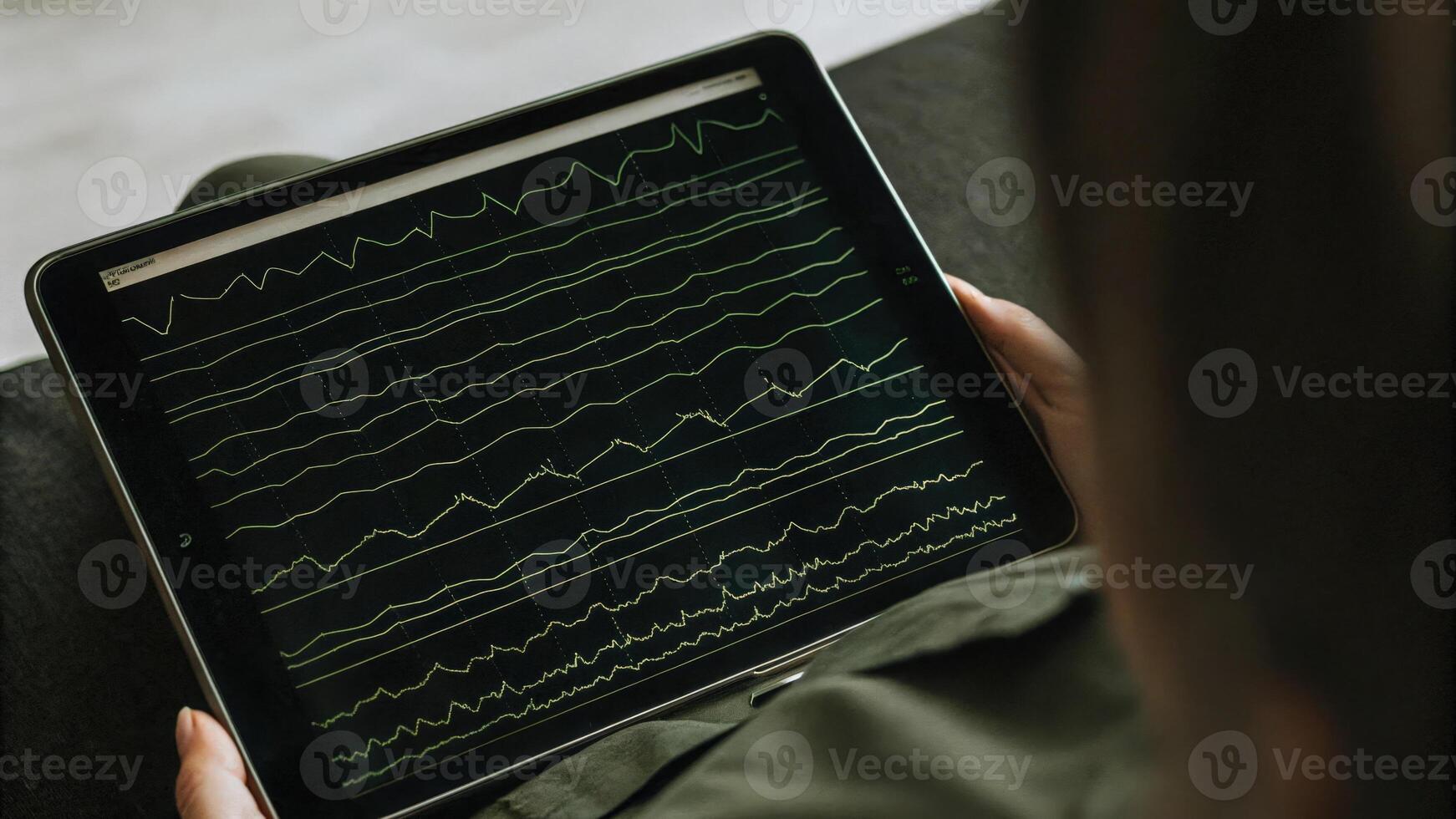 A closeup of the EEG sensor interface displaying realtime brainwave data on a tablet screen showing spikes and waves as the user meditates with the sensor visibly attached to their. photo