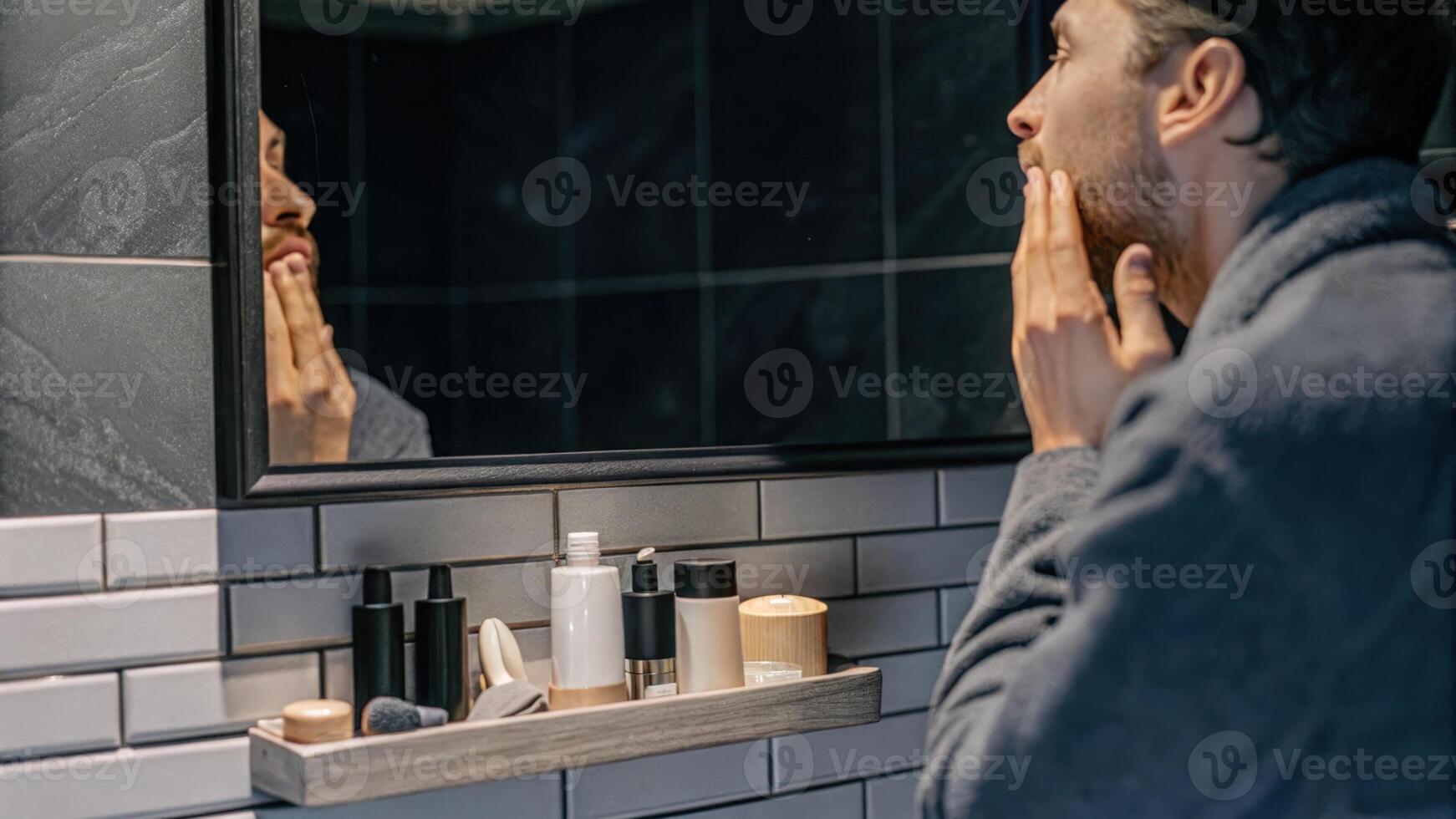 A thoughtful male figure gazing into a mirror showcasing transformative skincare routines with an array of environmentallyfriendly products neatly arranged around him.. photo
