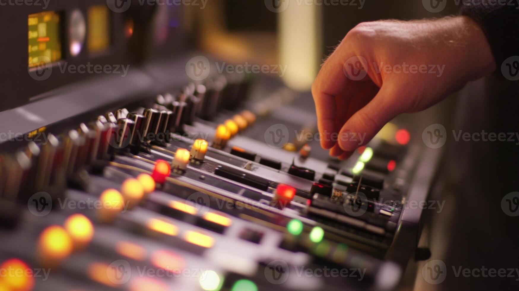 Sound engineer adjusting audio levels on a mixing console during a recording session photo