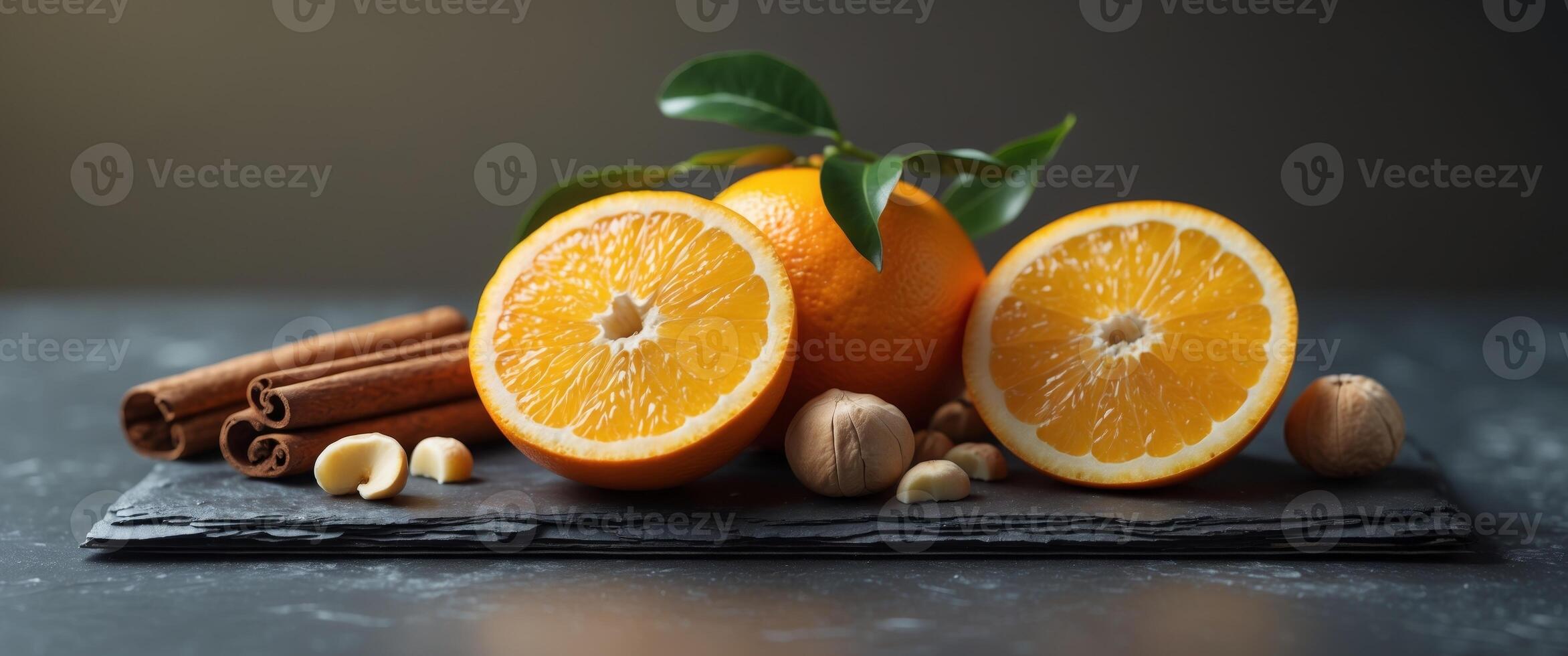 Fresh Orange Slices with Cinnamon Sticks and Hazelnuts on Dark Slate Surface for Healthy Recipe Ideas. photo