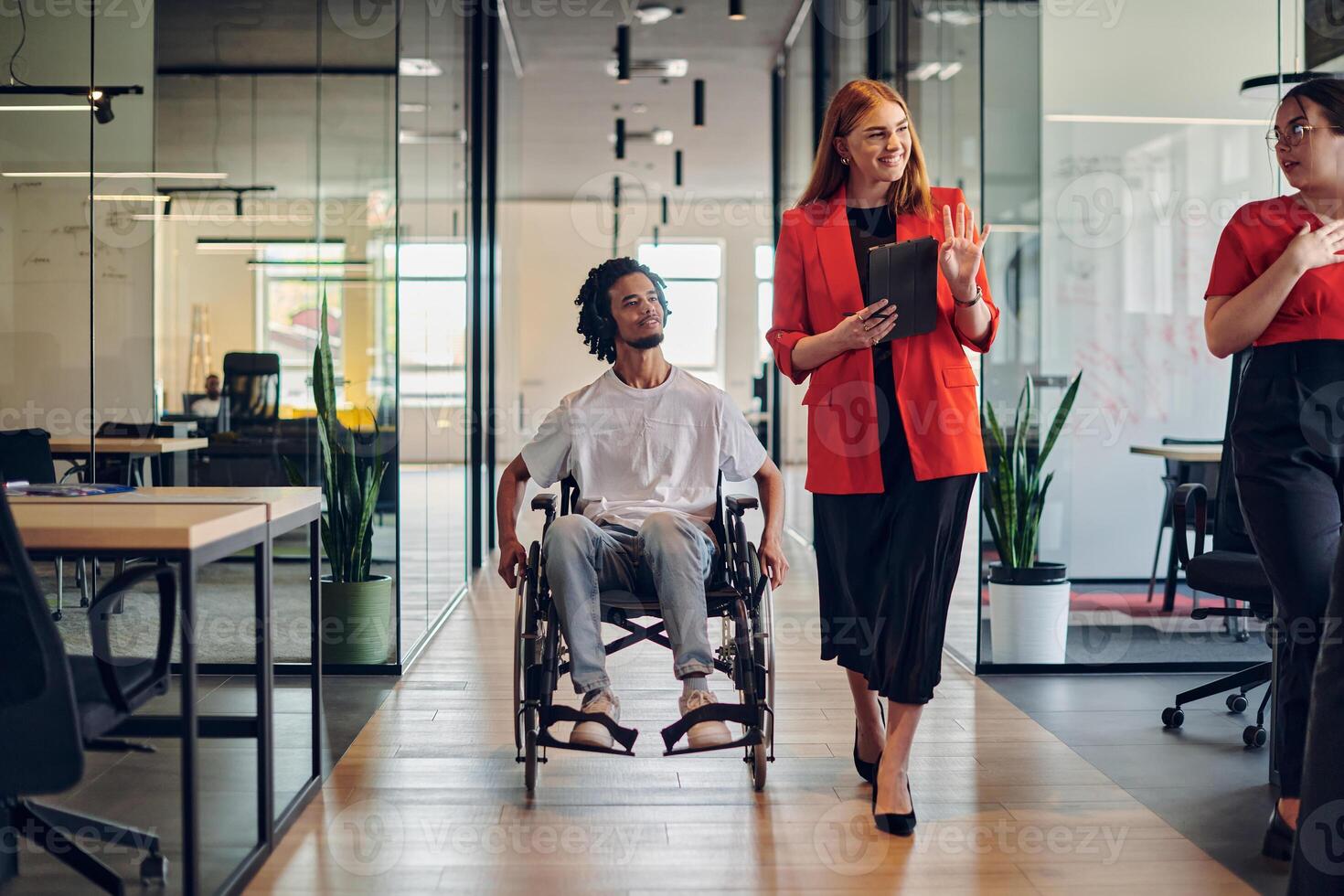 A group of young business people in a modern glass-walled office captures the essence of diversity and collaboration, while two colleagues, including an African American businessman in a wheelchair photo