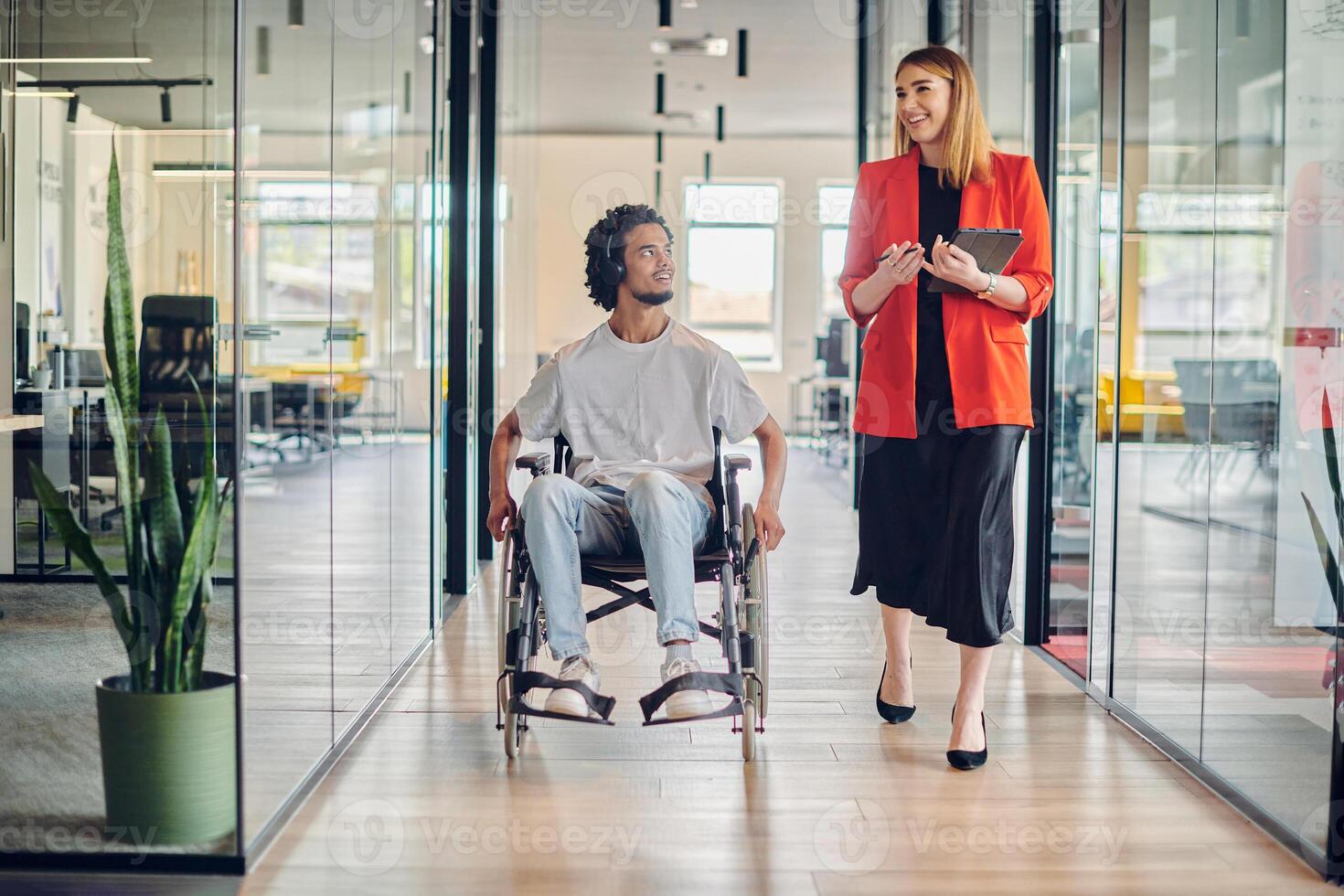 A group of young business people in a modern glass-walled office captures the essence of diversity and collaboration, while two colleagues, including an African American businessman in a wheelchair photo