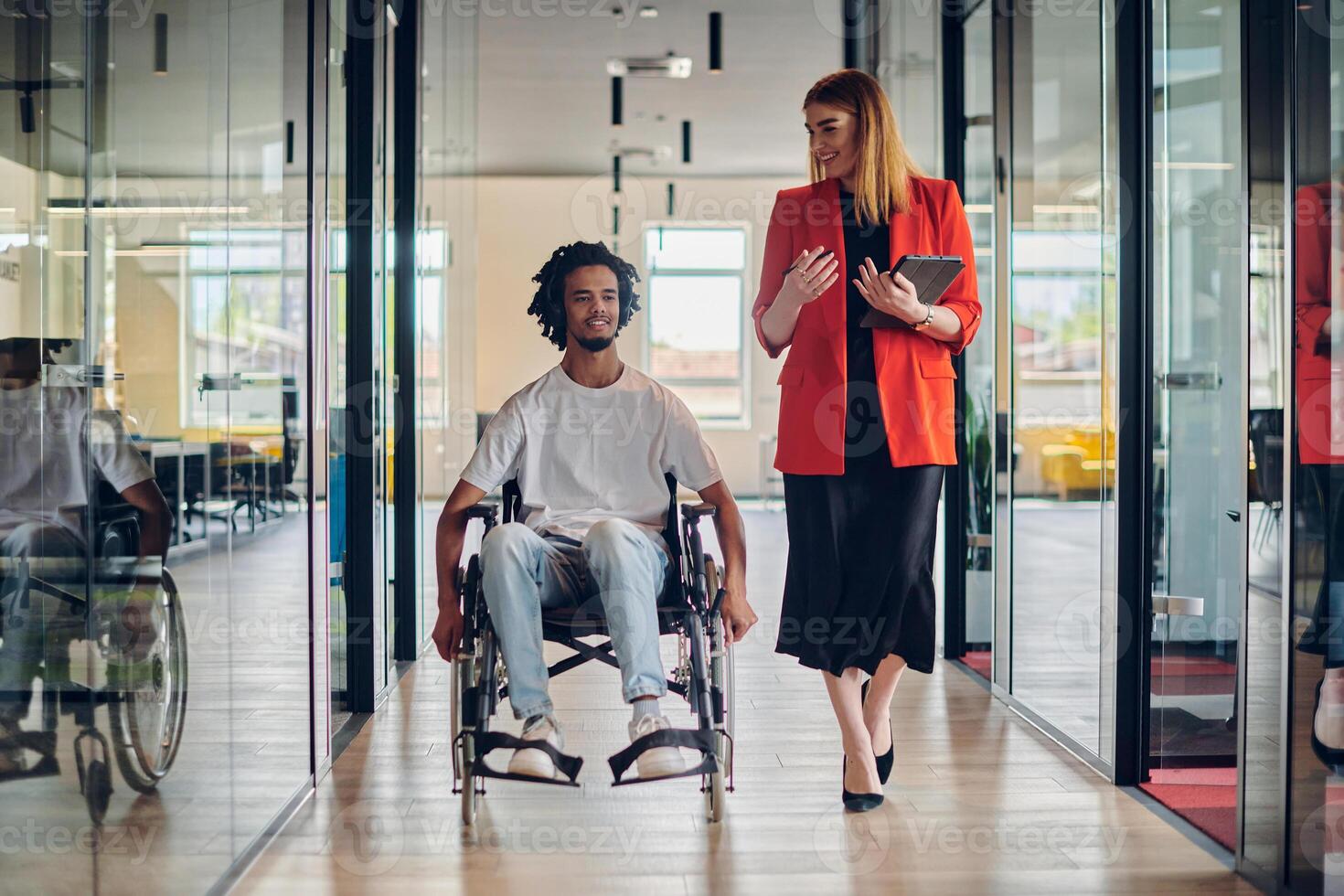A group of young business people in a modern glass-walled office captures the essence of diversity and collaboration, while two colleagues, including an African American businessman in a wheelchair photo
