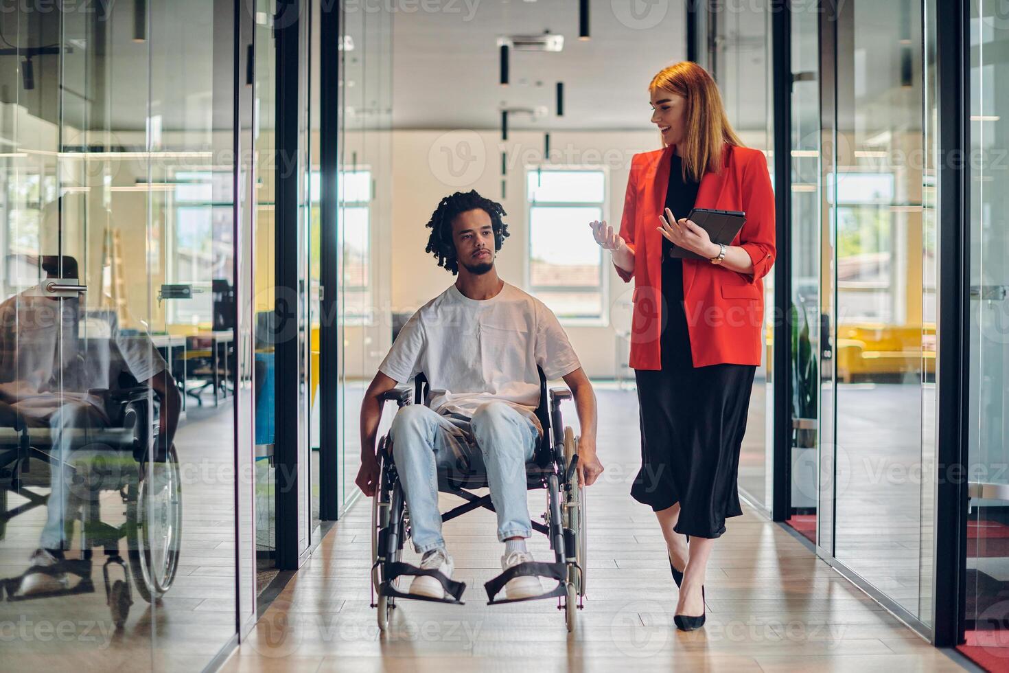A group of young business people in a modern glass-walled office captures the essence of diversity and collaboration, while two colleagues, including an African American businessman in a wheelchair photo