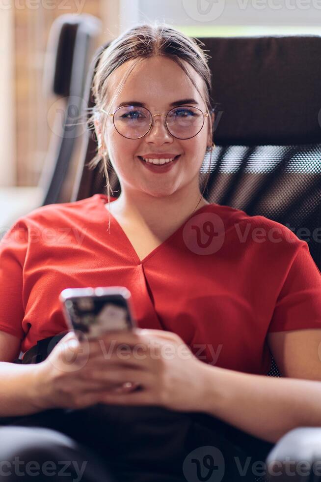A businesswoman resting on a short break from work in a modern startup coworking center, using her smartphone to unwind and recharge. photo