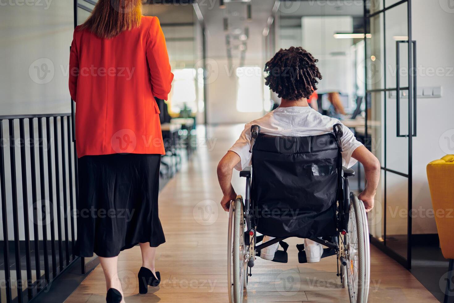 A group of young business people in a modern glass-walled office captures the essence of diversity and collaboration, while two colleagues, including an African American businessman in a wheelchair photo