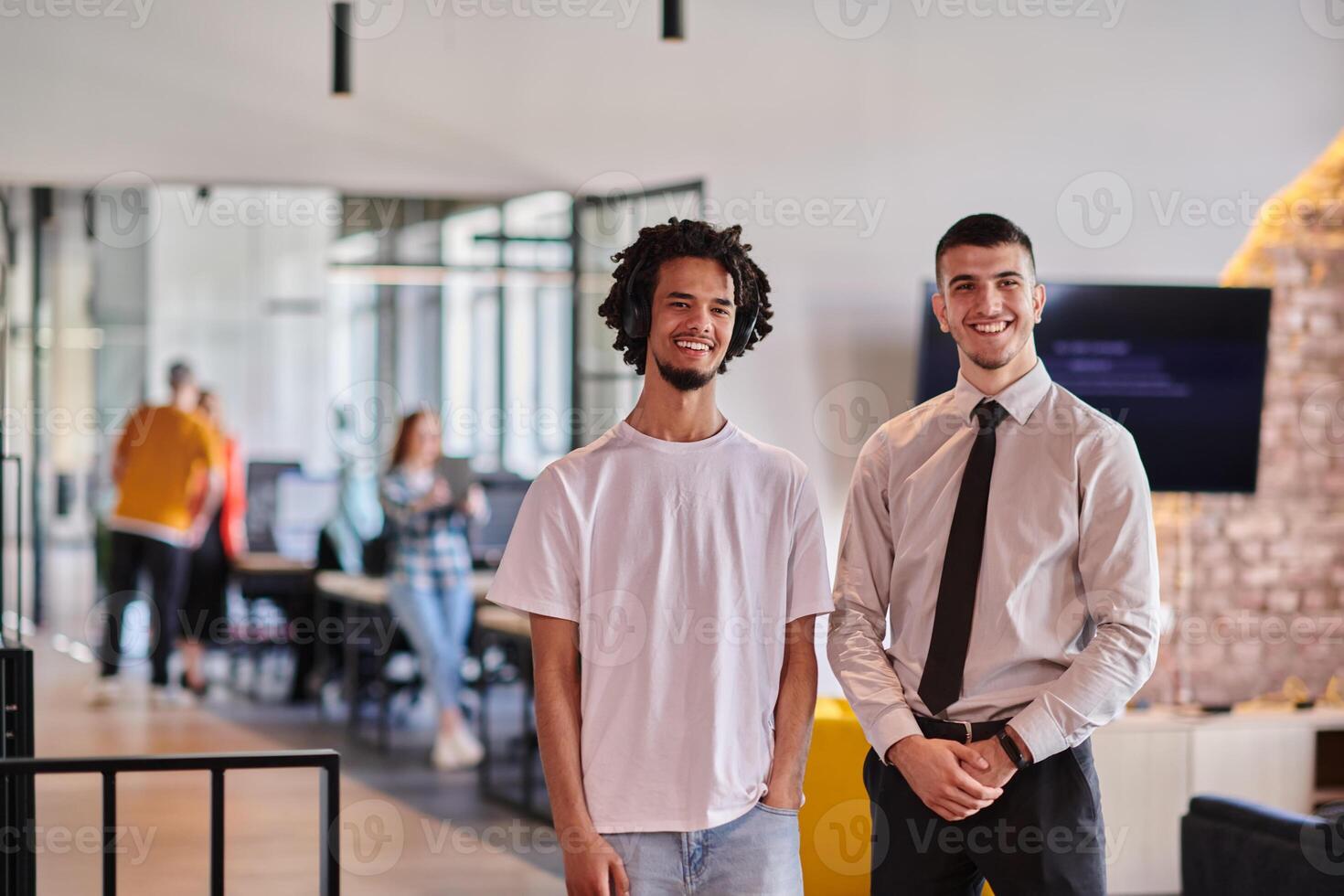 A group of colleagues, including an African American businessman and a young leader in a shirt and tie, pose together in a modern coworking center office, representing a dynamic blend of photo
