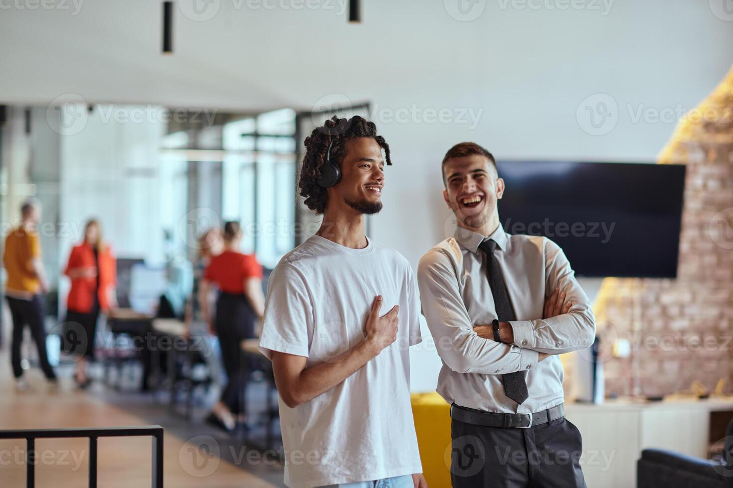 A group of colleagues, including an African American businessman and a young leader in a shirt and tie, pose together in a modern coworking center office, representing a dynamic blend of photo