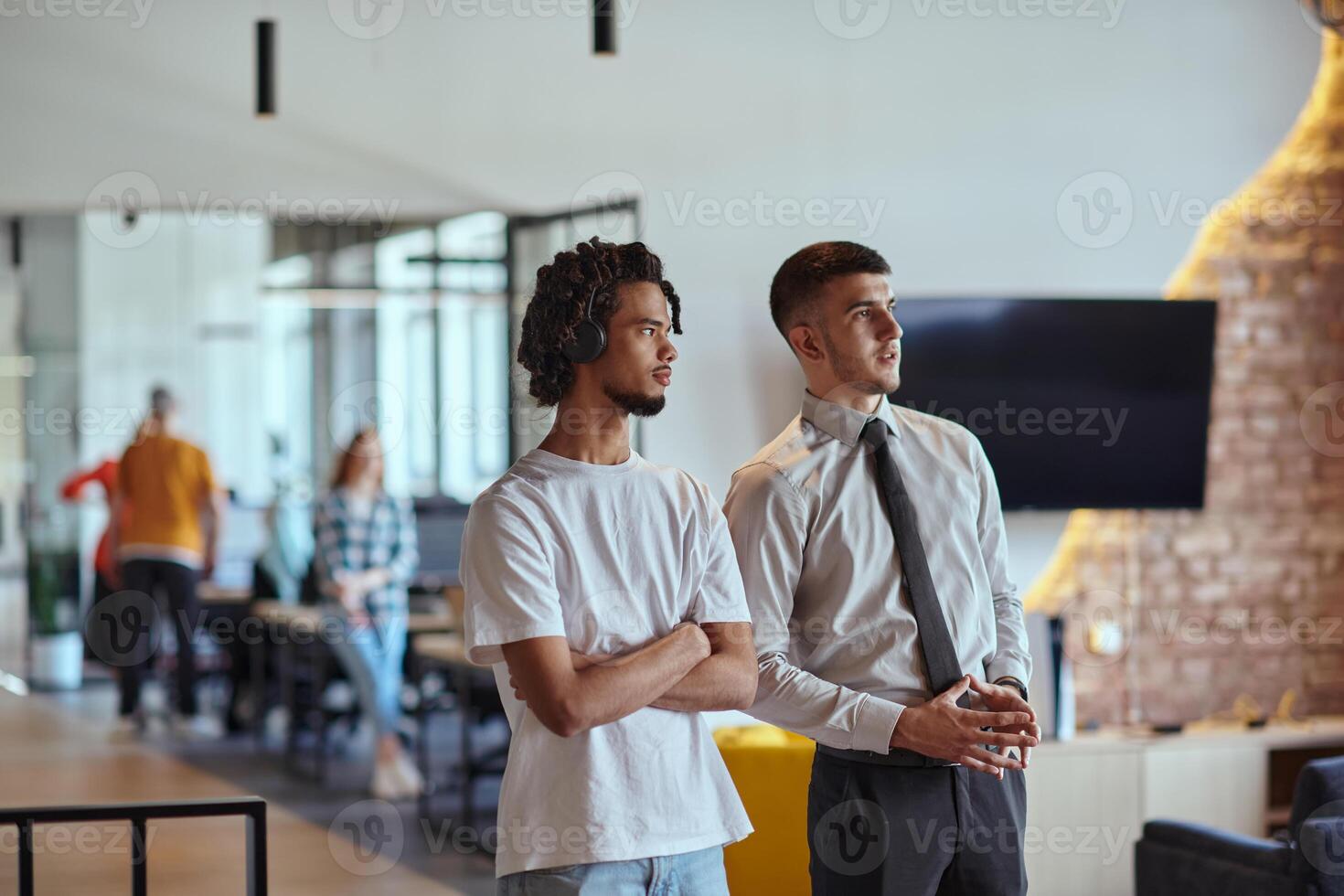 A group of colleagues, including an African American businessman and a young leader in a shirt and tie, pose together in a modern coworking center office, representing a dynamic blend of photo