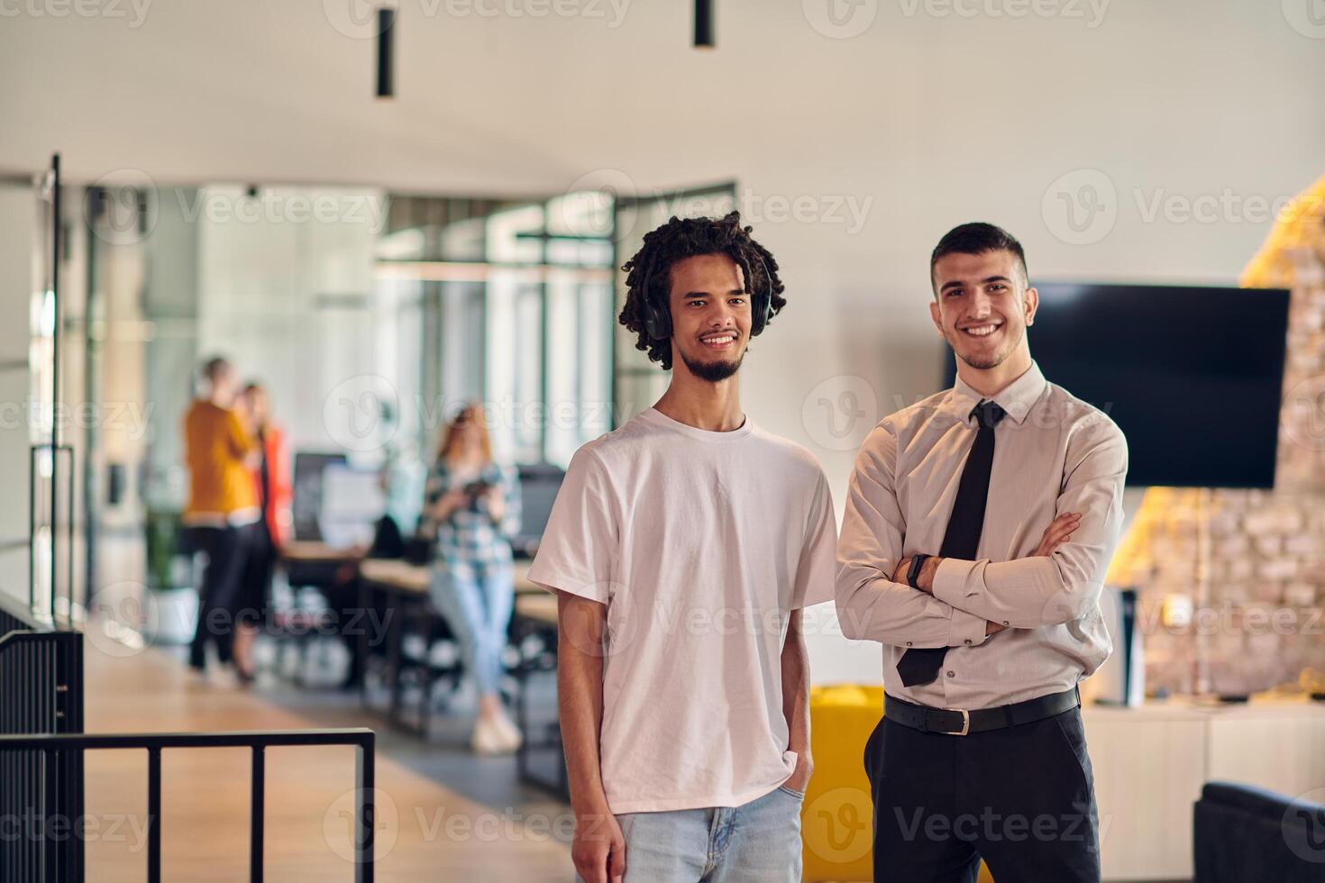 A group of colleagues, including an African American businessman and a young leader in a shirt and tie, pose together in a modern coworking center office, representing a dynamic blend of photo