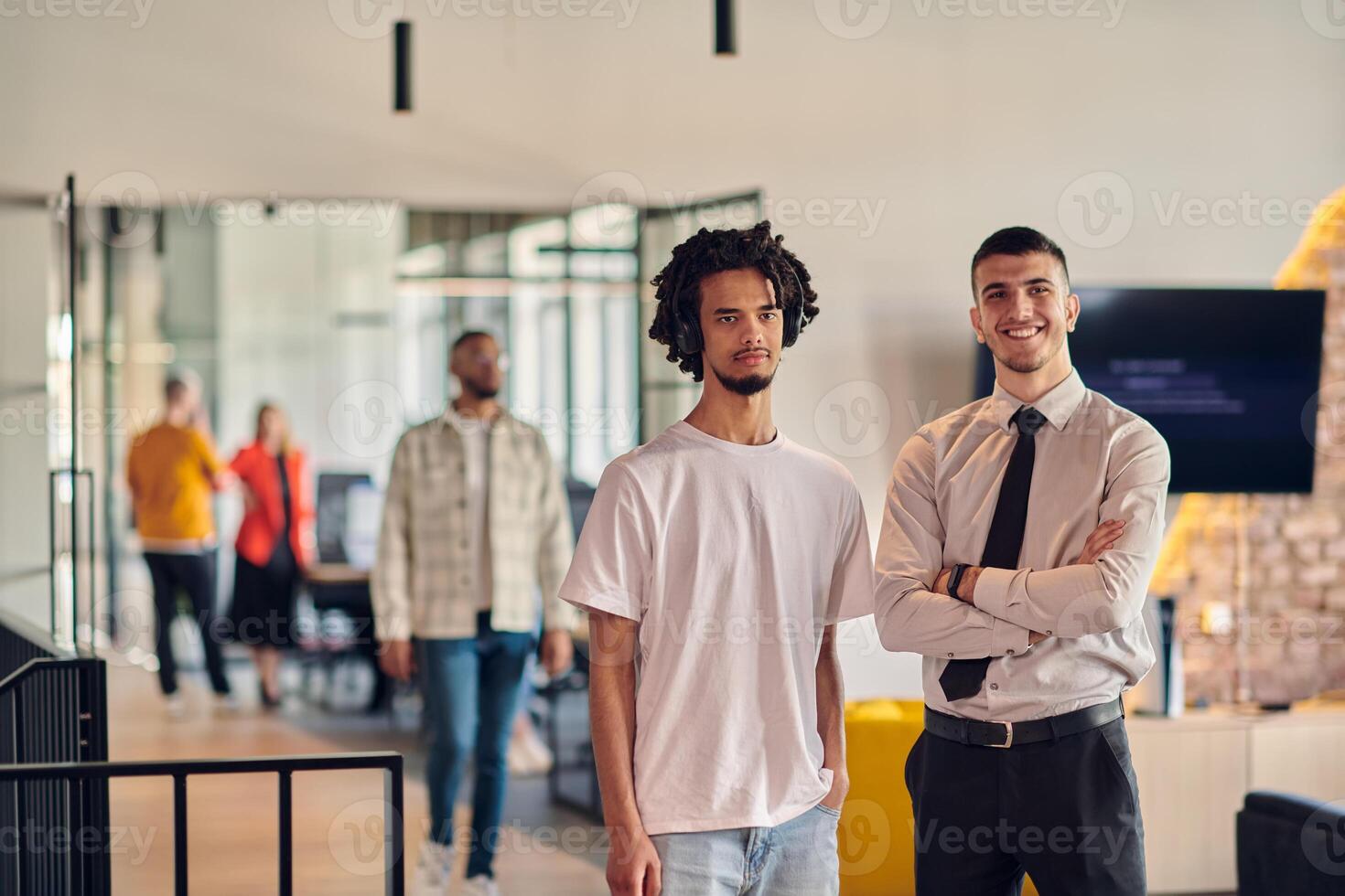 A group of colleagues, including an African American businessman and a young leader in a shirt and tie, pose together in a modern coworking center office, representing a dynamic blend of photo
