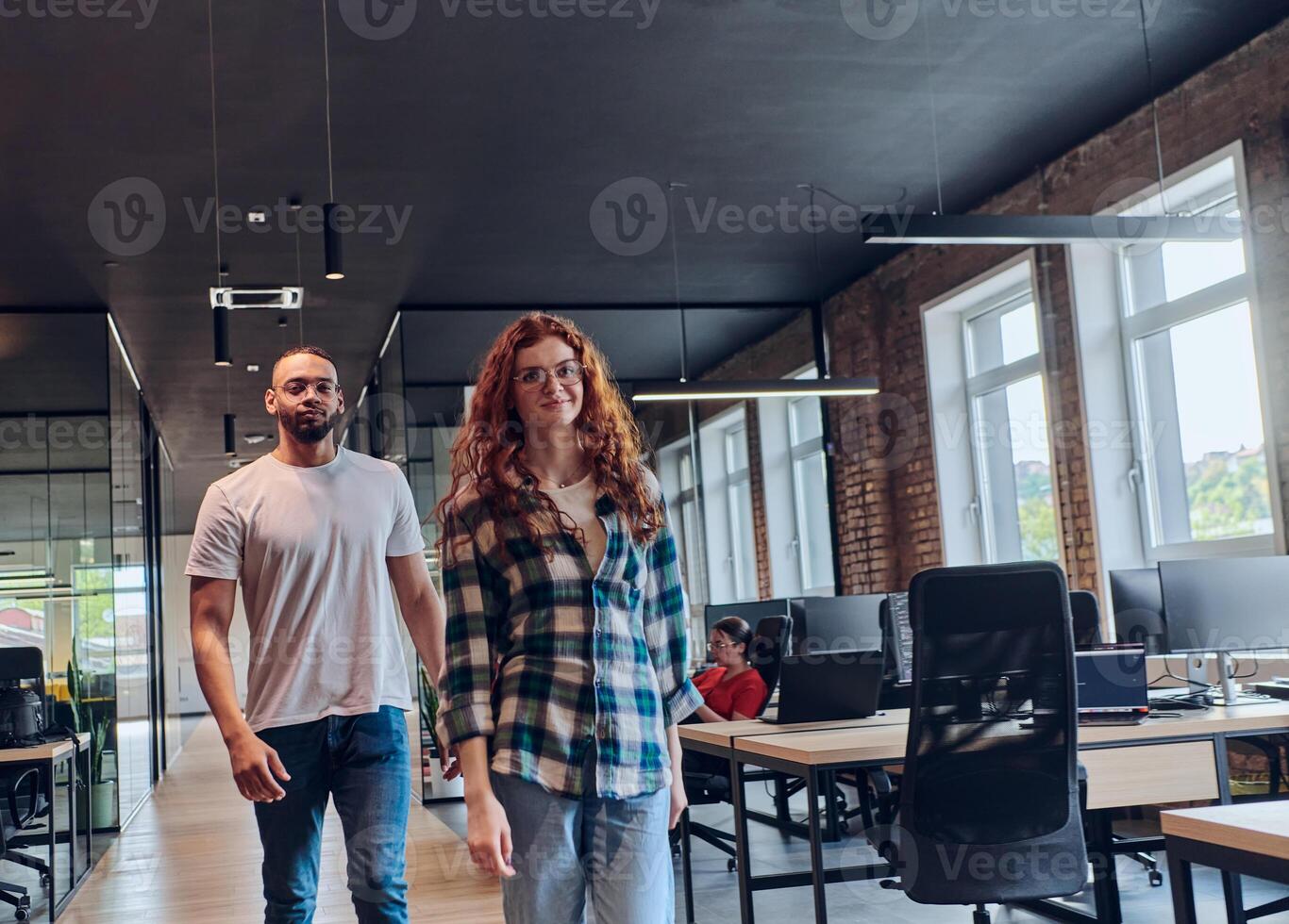 A young African American businessman and a modern businesswoman with orange hair stand side by side, arms crossed, exuding confidence and unity in a contemporary office setting, epitomizing dynamic photo