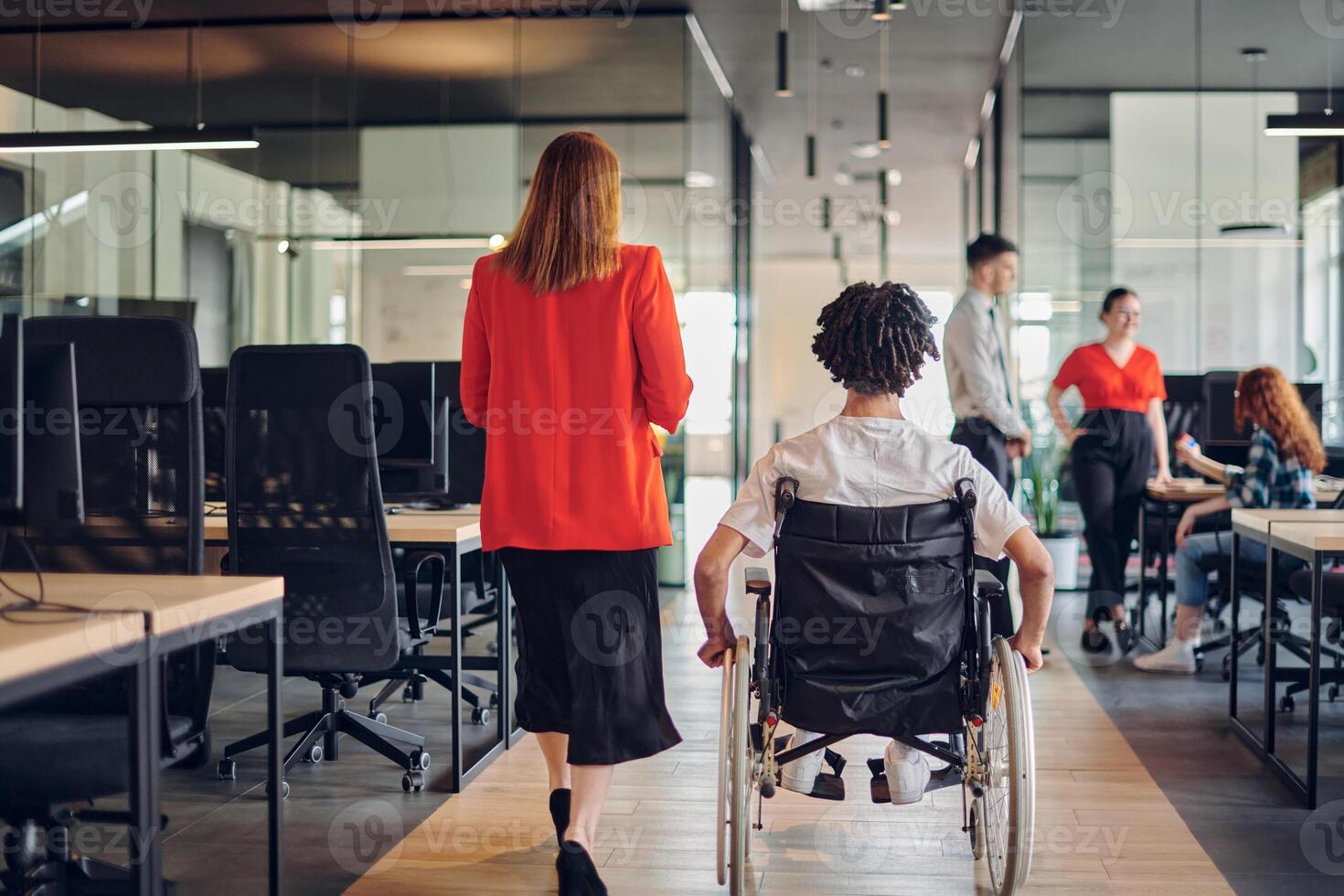 A group of young business people in a modern glass-walled office captures the essence of diversity and collaboration, while two colleagues, including an African American businessman in a wheelchair photo