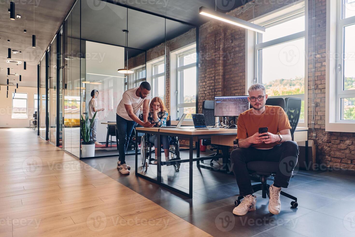 A diverse group of business professionals collaborates in a modern startup coworking center, utilizing a mix of paper-based and technological tools such as mobile phones and computers to collectively photo
