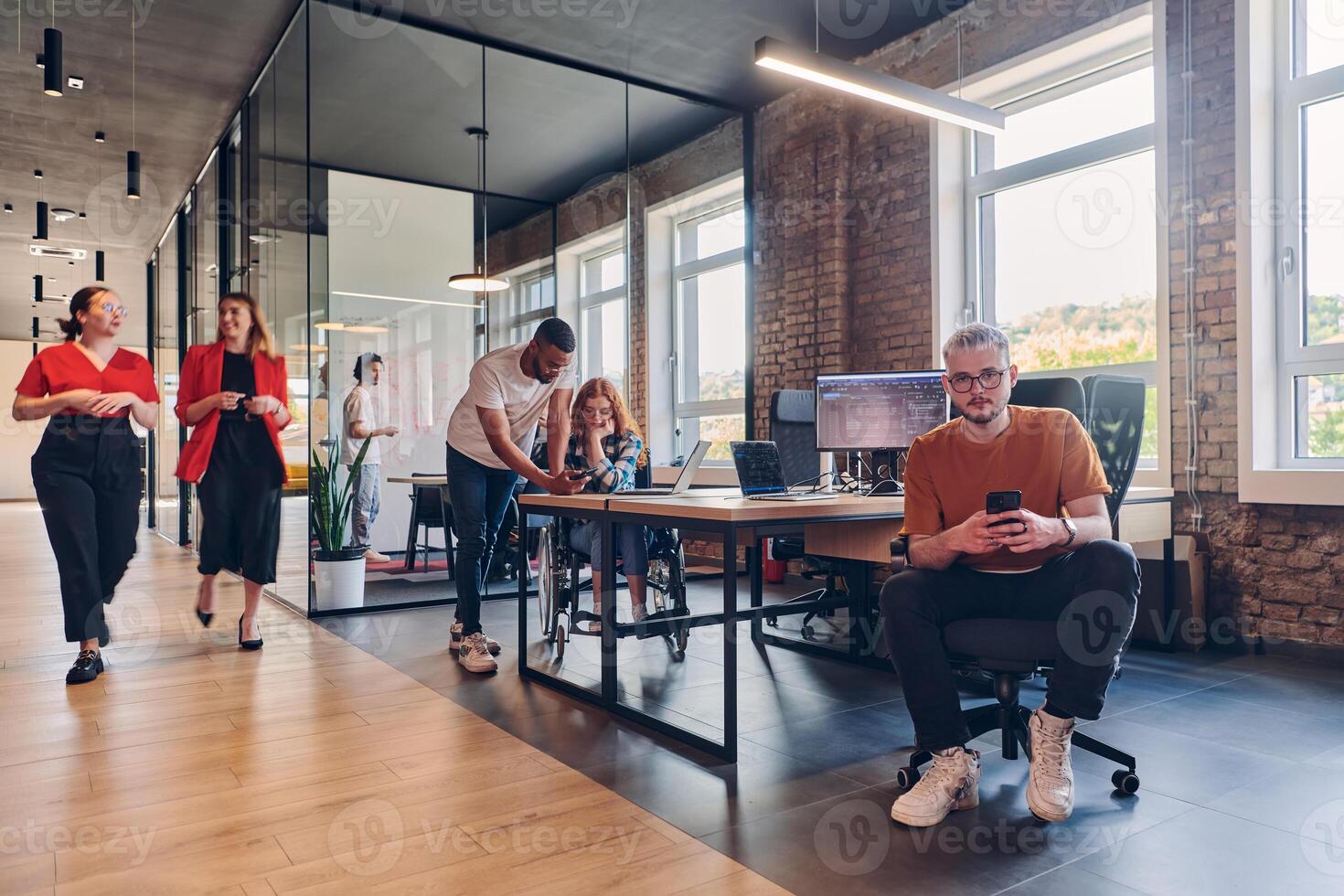 A diverse group of business professionals collaborates in a modern startup coworking center, utilizing a mix of paper-based and technological tools such as mobile phones and computers to collectively photo