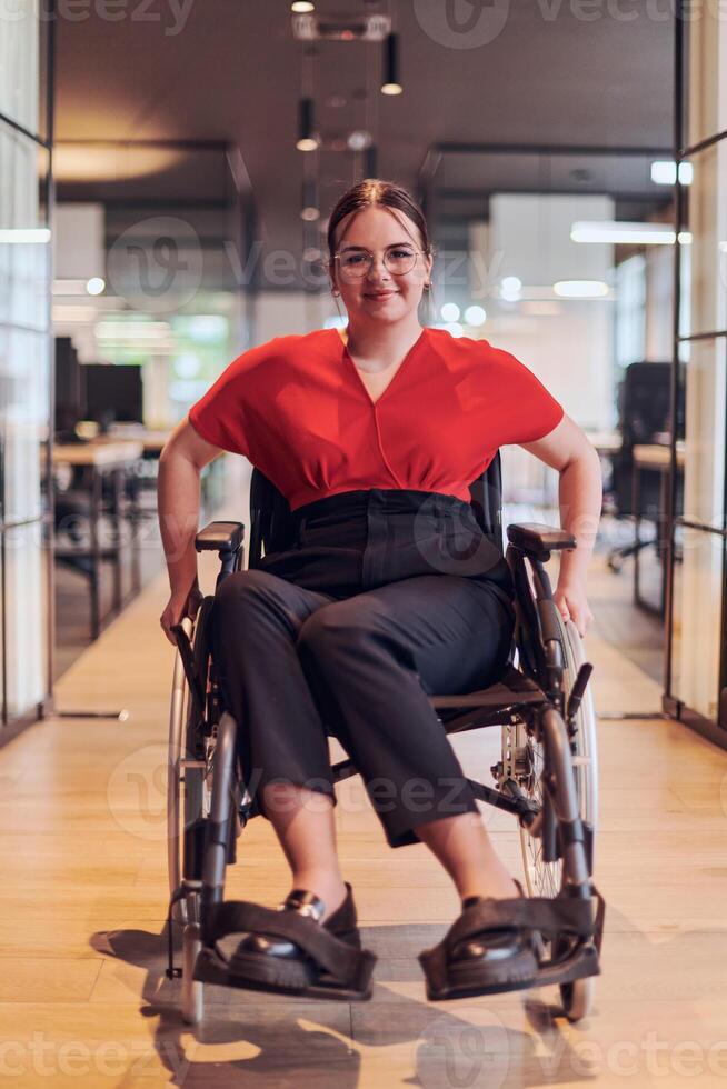 A modern young businesswoman in a wheelchair is surrounded by an inclusive workspace with glass-walled offices, embodying determination and innovation in the business world photo