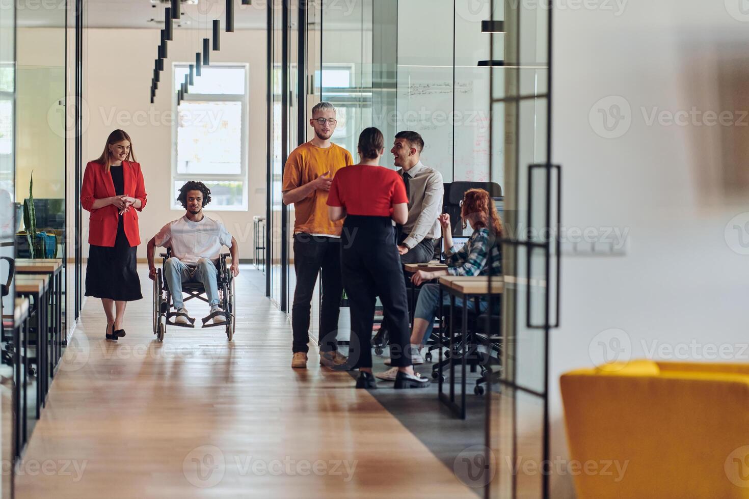 A group of young business people in a modern glass-walled office captures the essence of diversity and collaboration, while two colleagues, including an African American businessman in a wheelchair photo